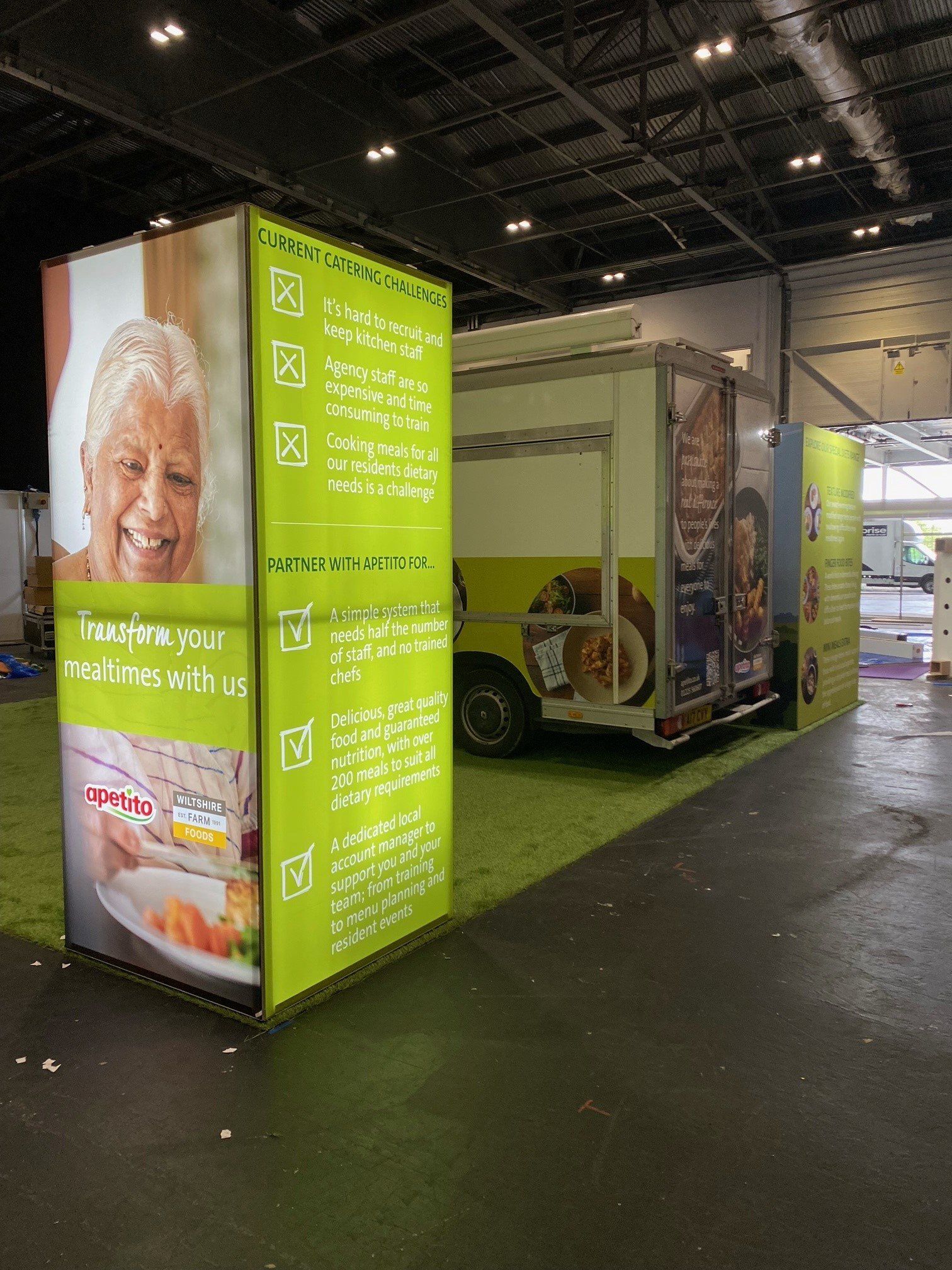 A food truck is parked in a room next to a display of food.