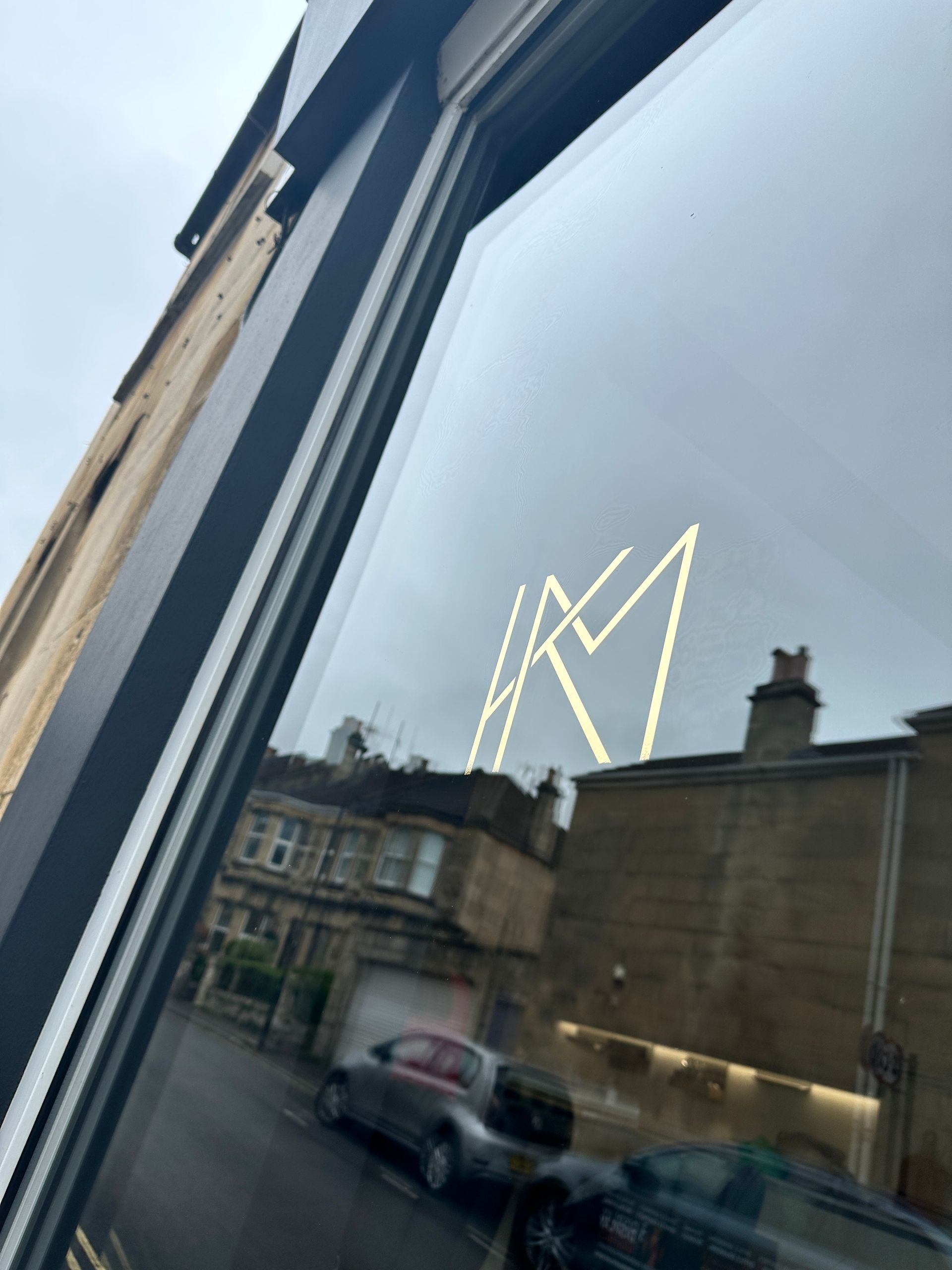 The letter m is reflected in the window of a building