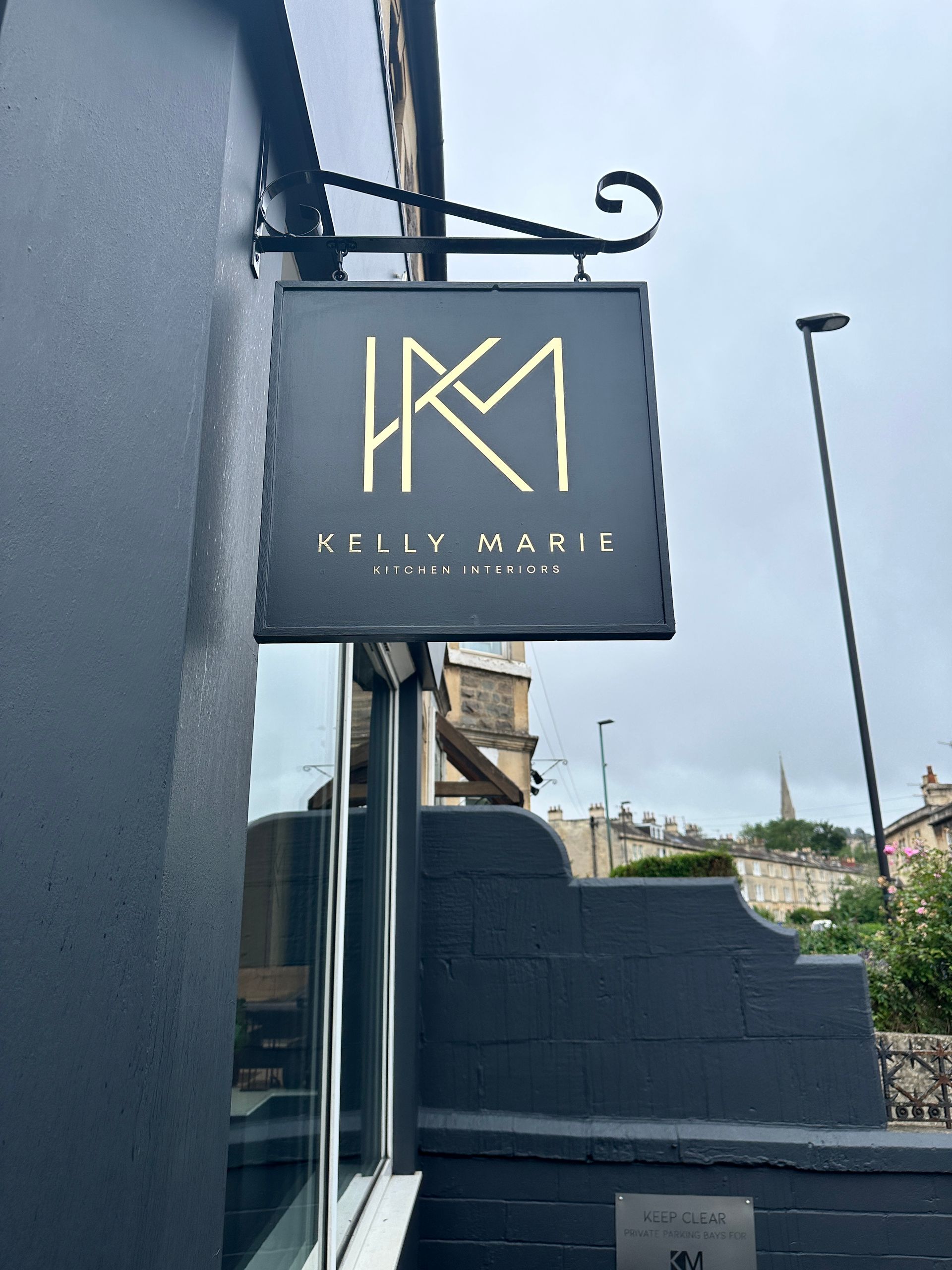A sign for kelly marie hangs from the side of a building
