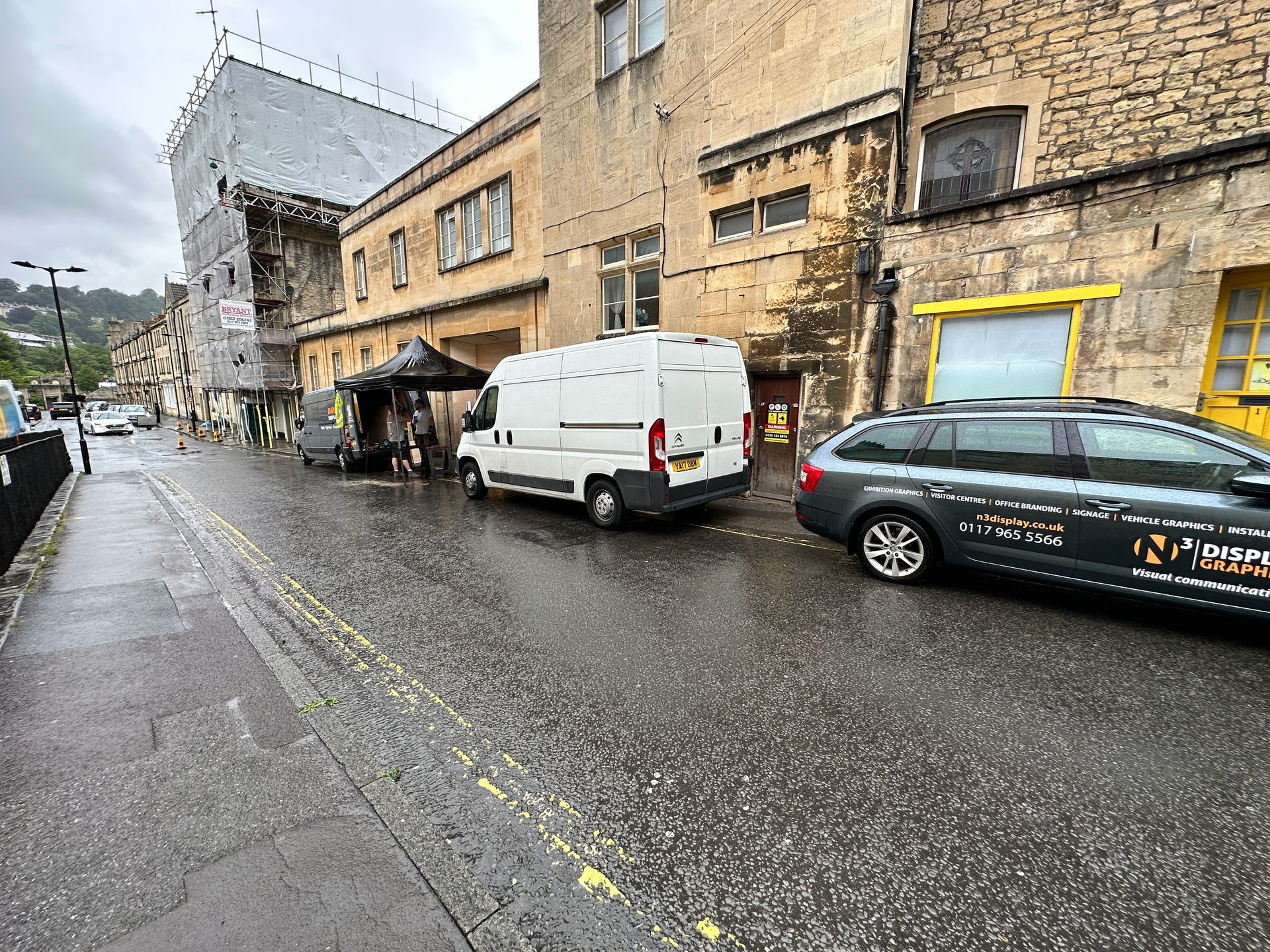 A white van is parked on the side of the road in front of a building.