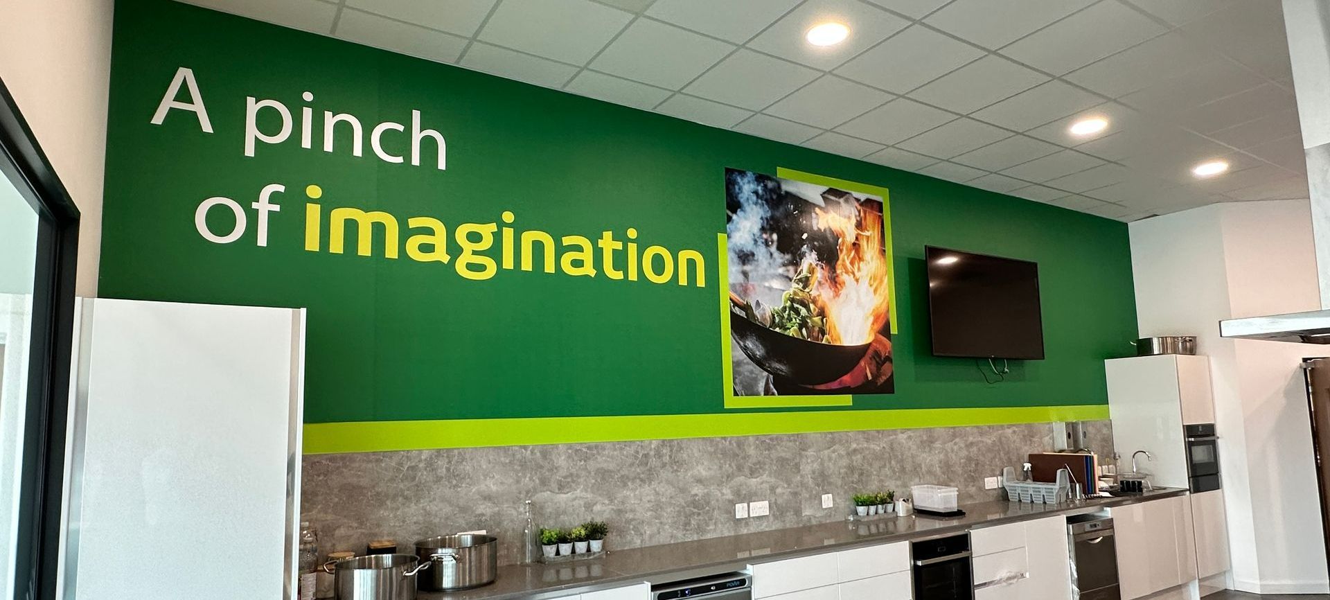 A kitchen with a green wall that says `` a pinch of imagination ''.