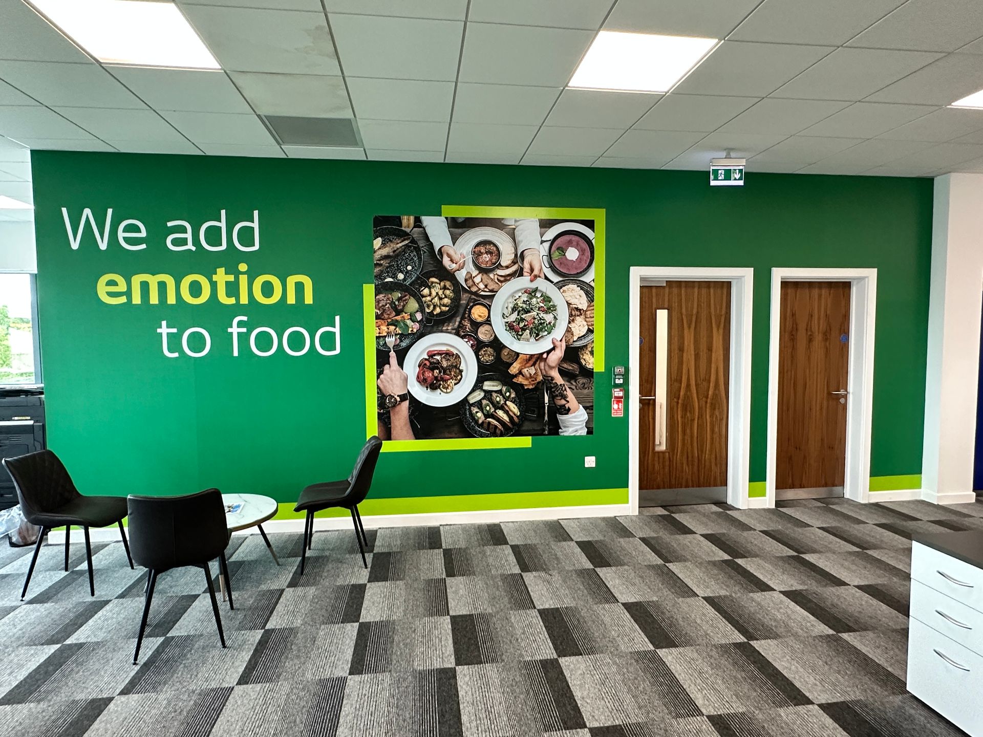 A room with a green wall that says `` we add emotion to food ''