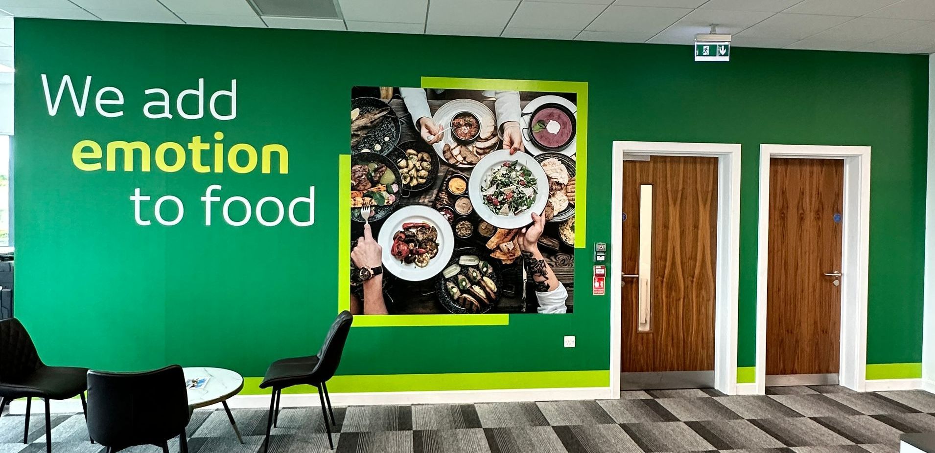A green wall with a picture on it that says `` we add emotion to food ''.