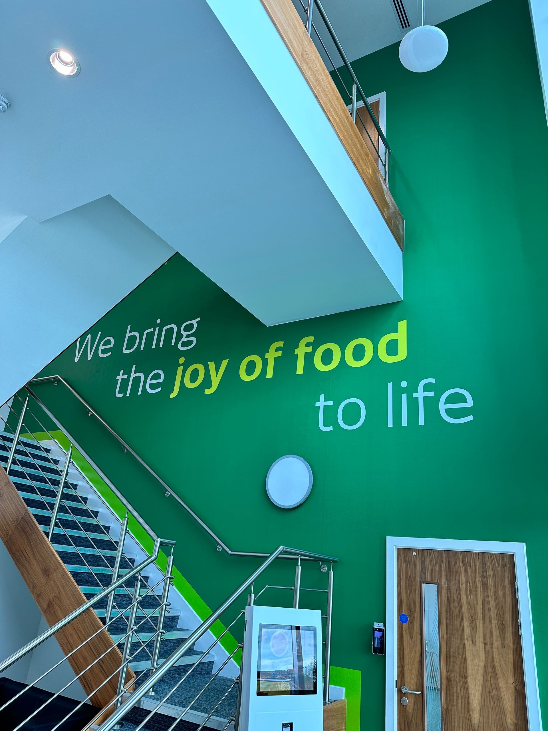 A green wall with the words we bring the joy of food to life written on it
