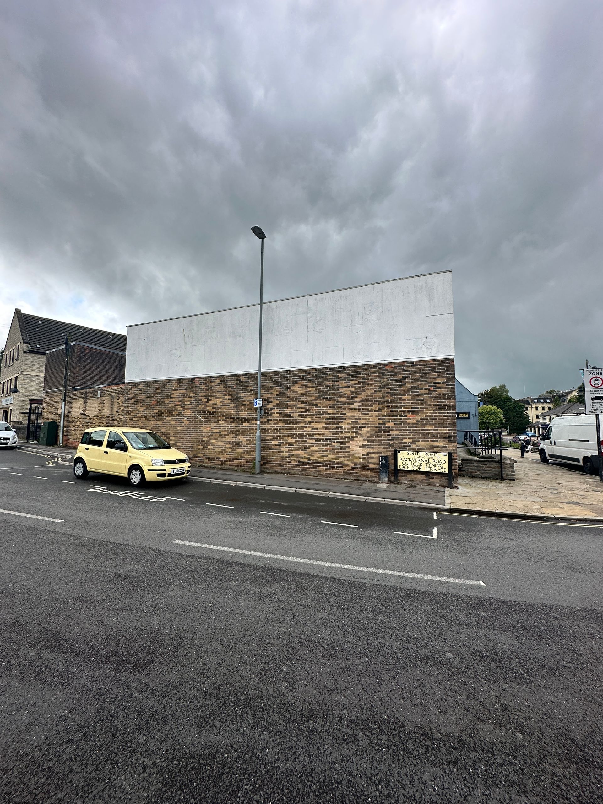 A yellow car is parked on the side of the road in front of a building.