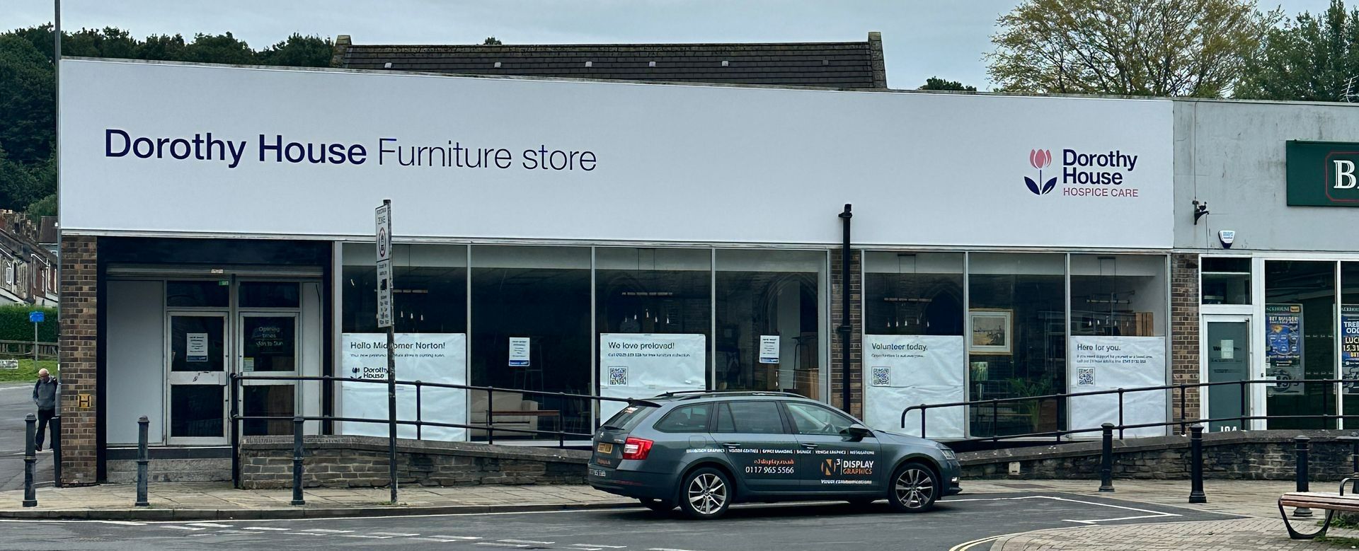 A car is parked in front of a store called dorothy house furniture store.