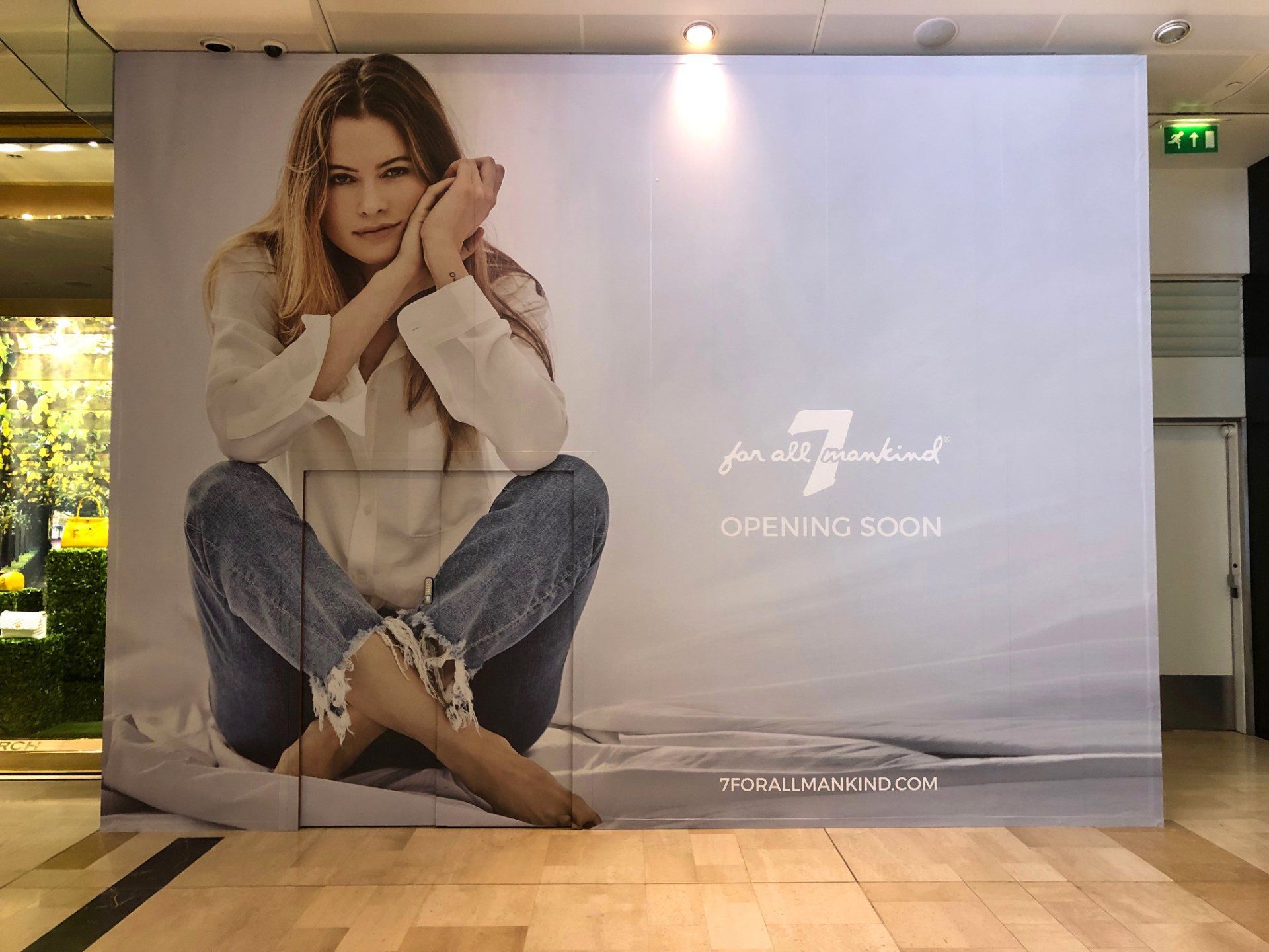 A large billboard with a picture of a woman sitting on the floor.