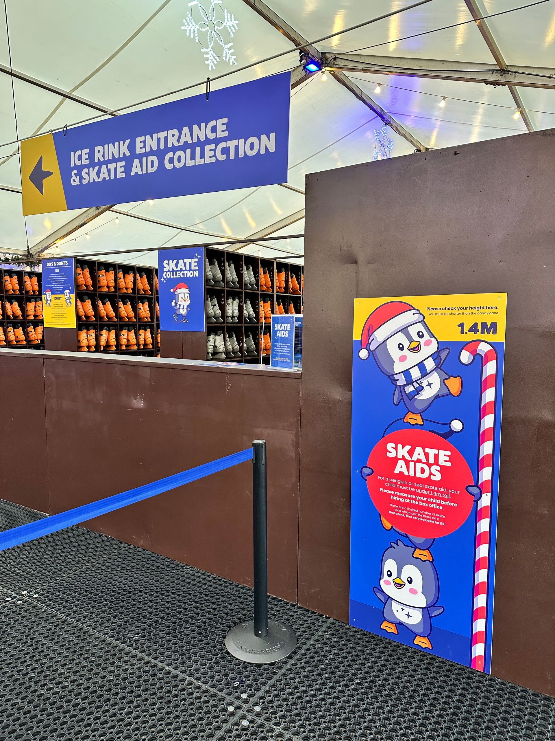 A sign for skate aids is next to a sign for ice rink entrance