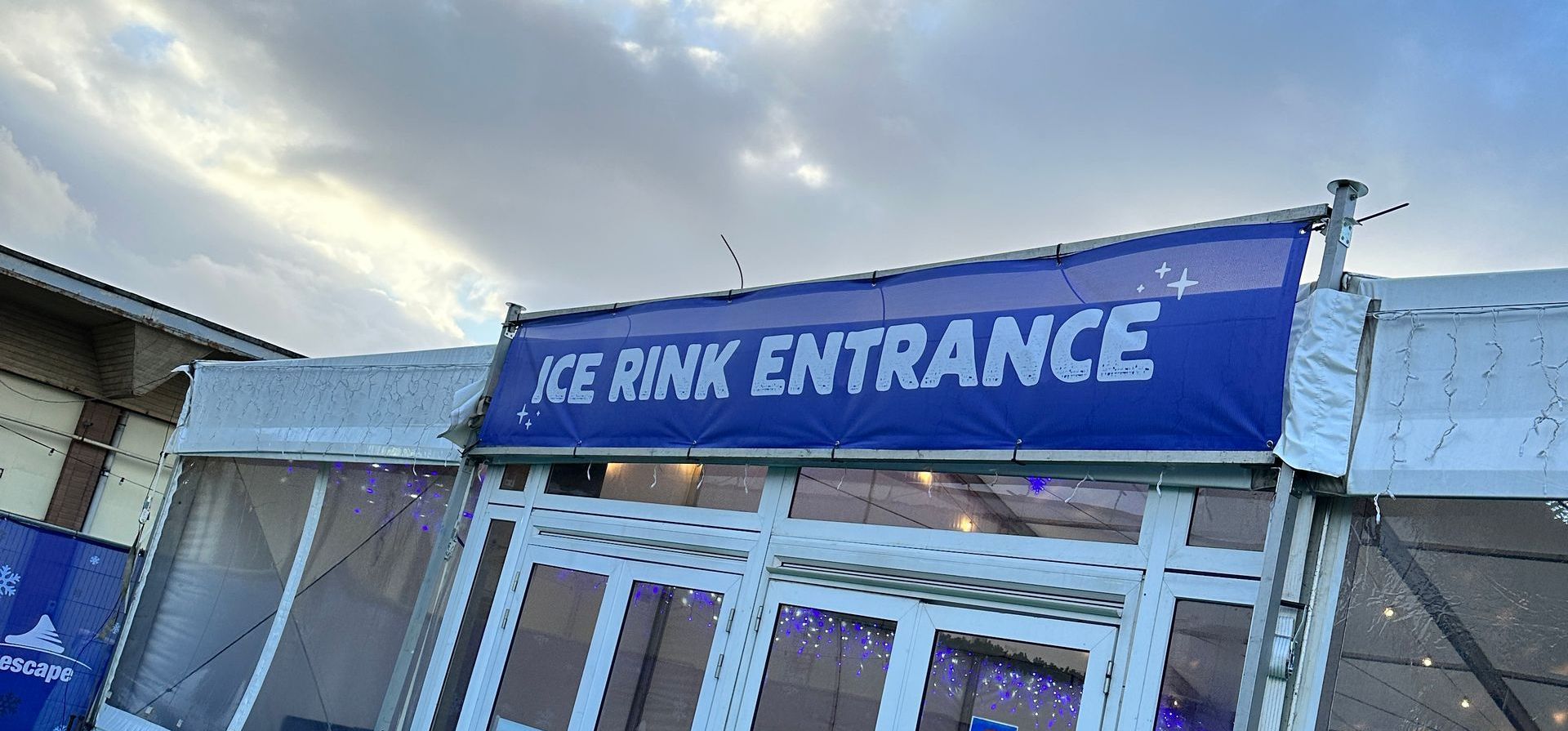A blue and white sign that says ice rink entrance