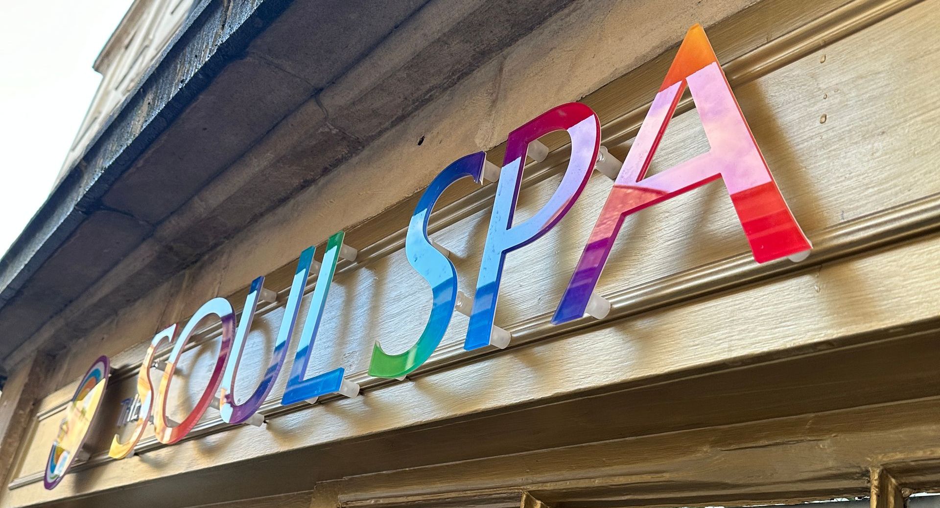 A colorful sign for a spa is on the side of a building.