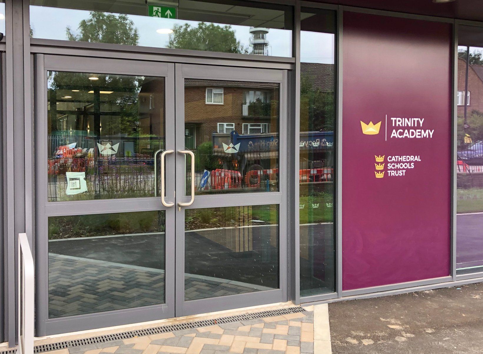 A building with a purple sign that says trinity academy on it.