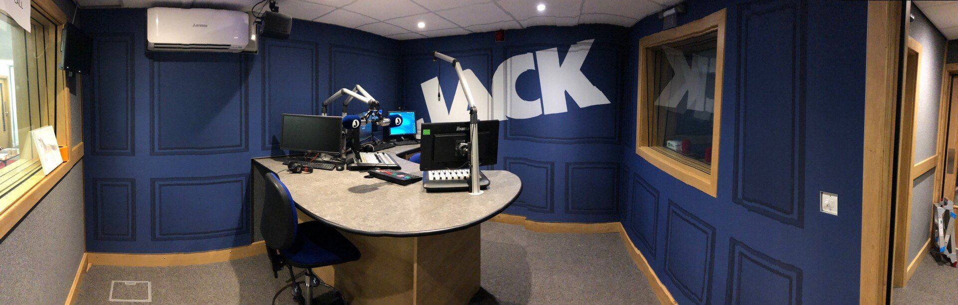 A radio studio with blue walls and a desk.
