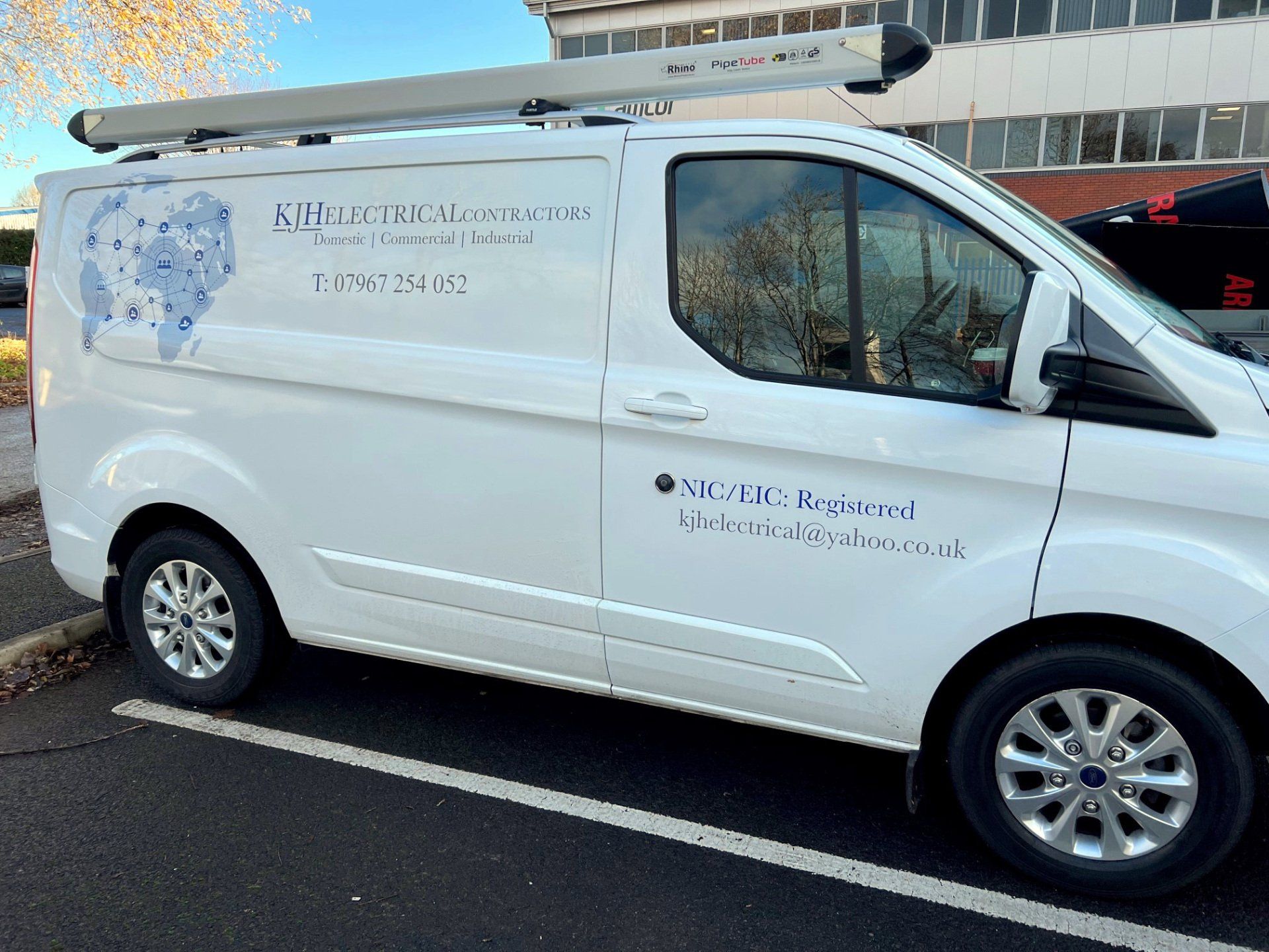 A white van is parked in a parking lot in front of a building.