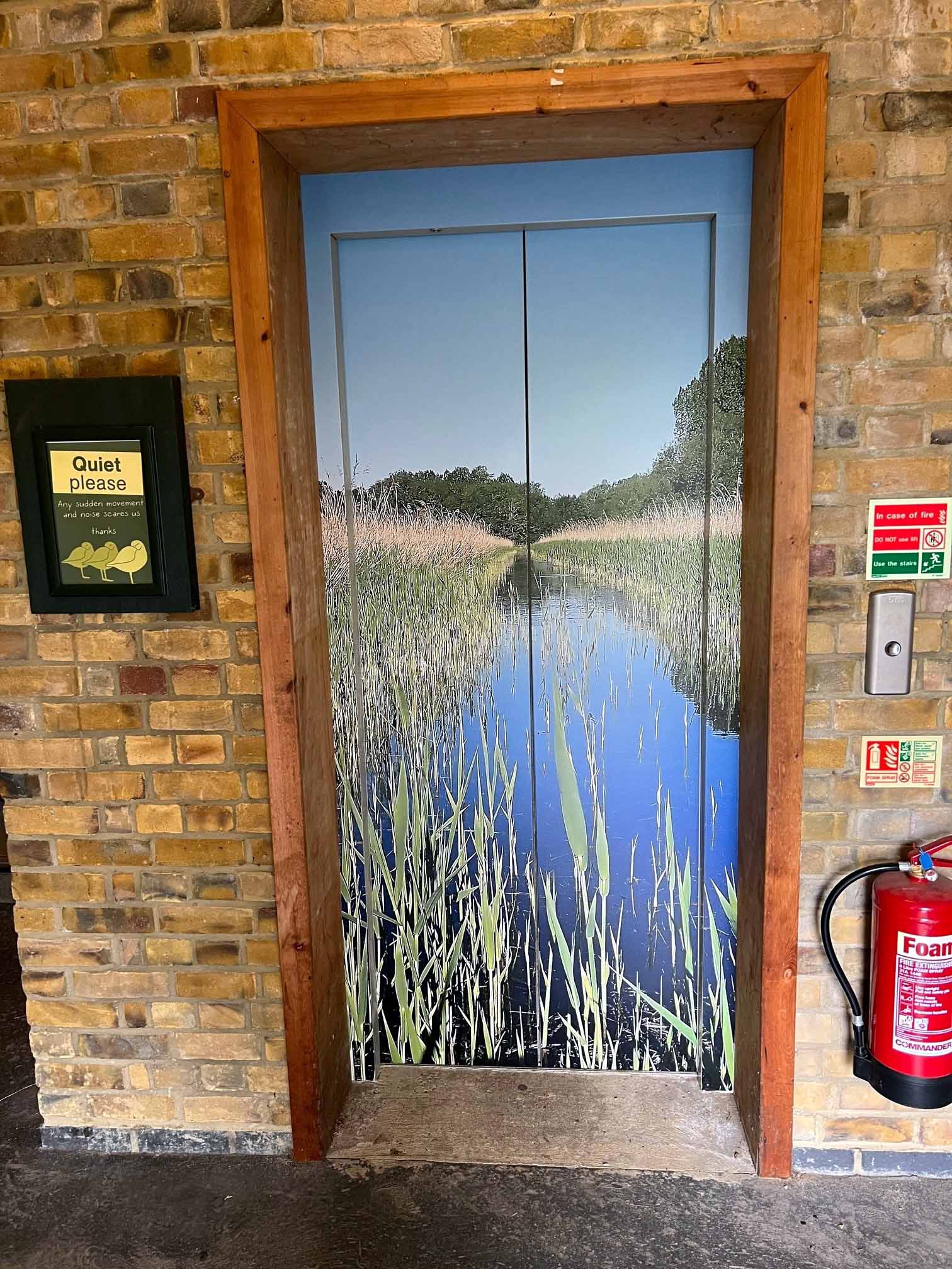 An elevator with a picture of a river on the door.