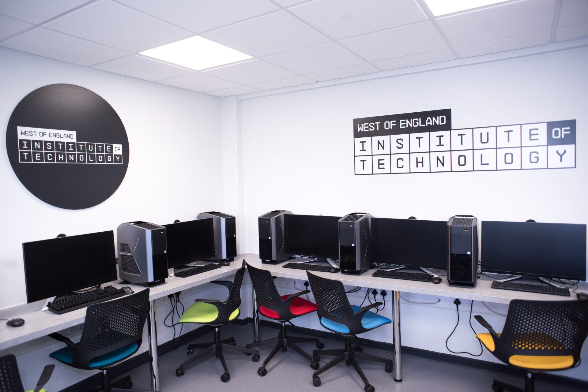 A room with a lot of computer monitors and chairs
