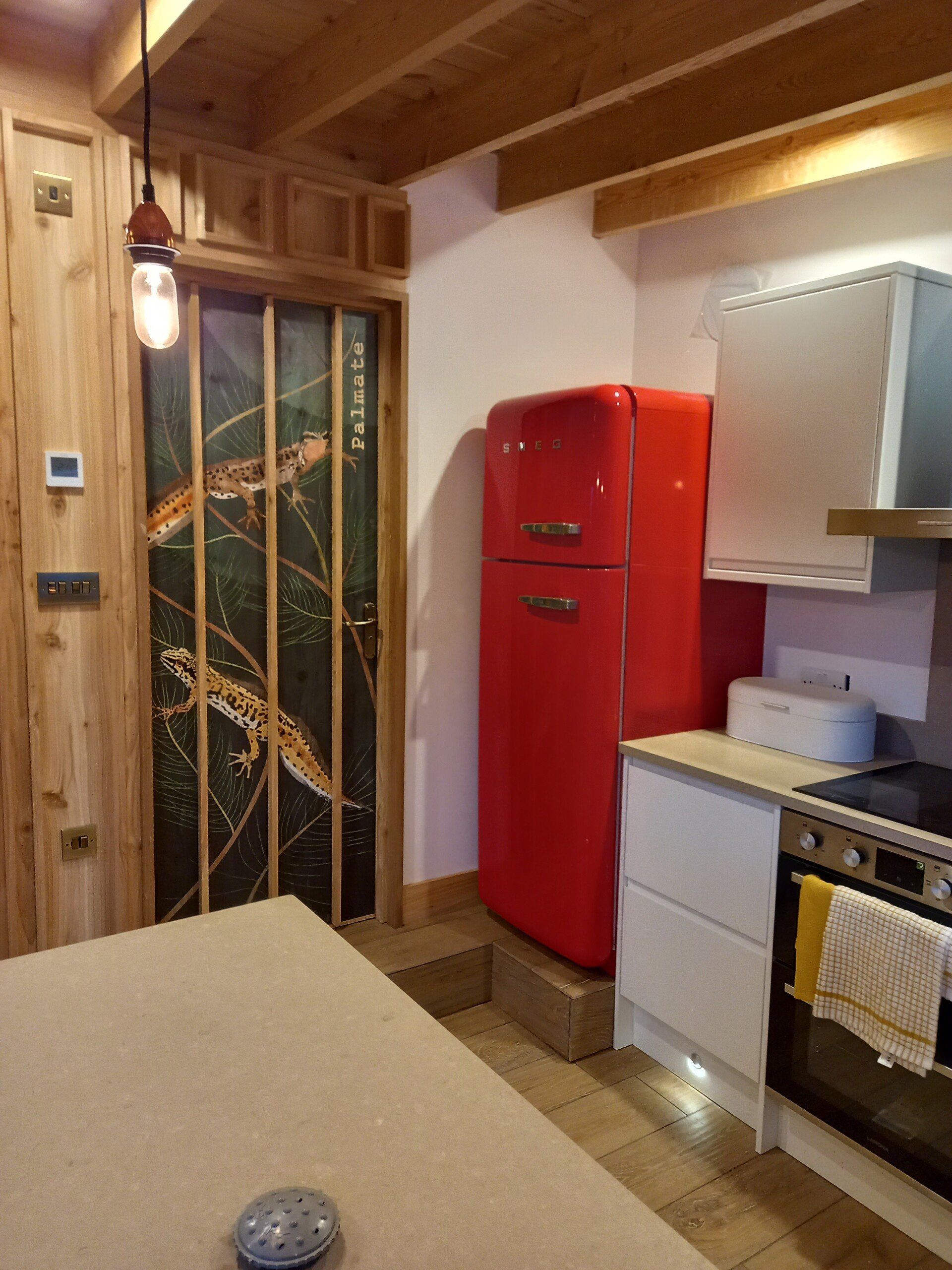 A kitchen with a red refrigerator and a stove