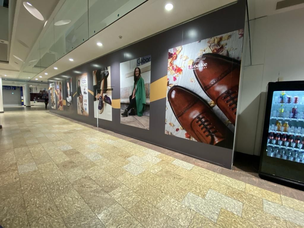 A long hallway with a lot of pictures on the wall and a vending machine.