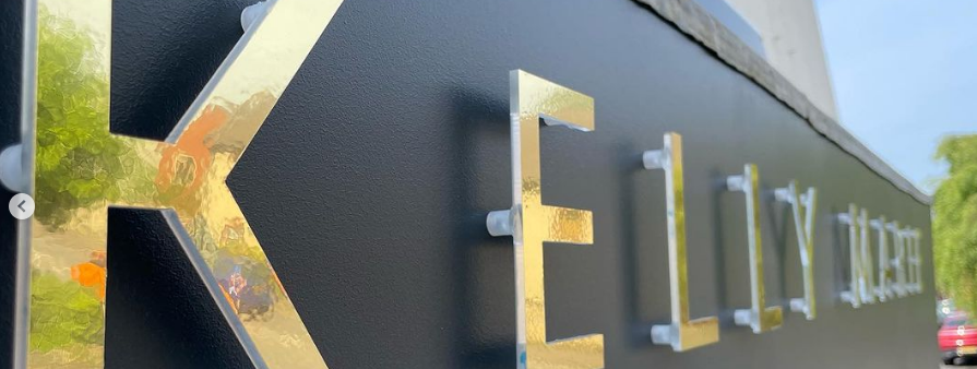 A close up of a black sign with gold letters on it.