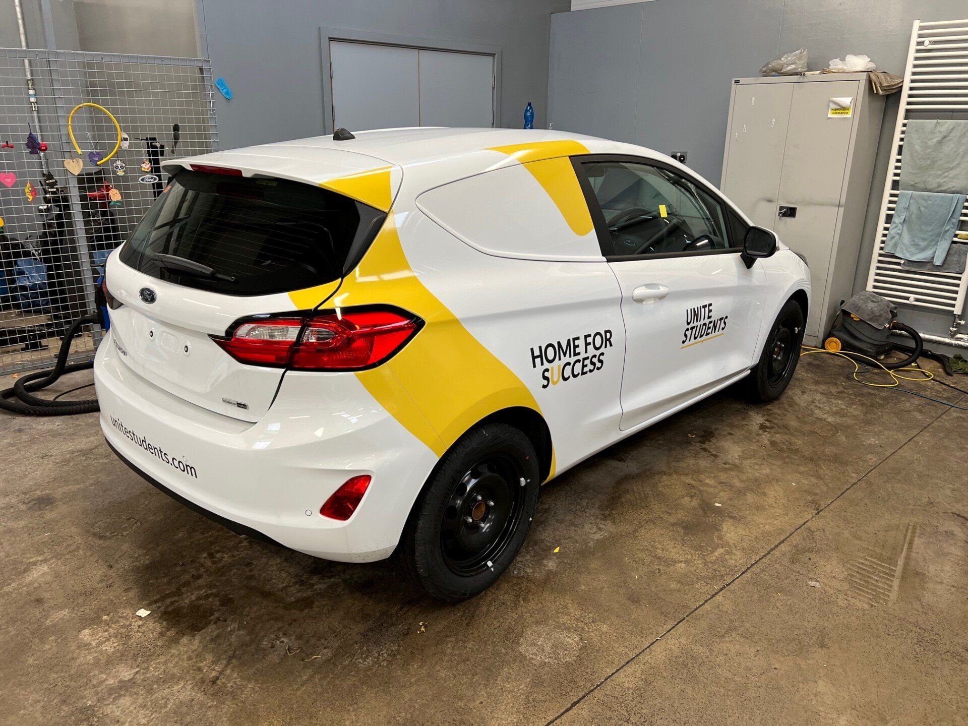 A white and yellow car is parked in a garage.