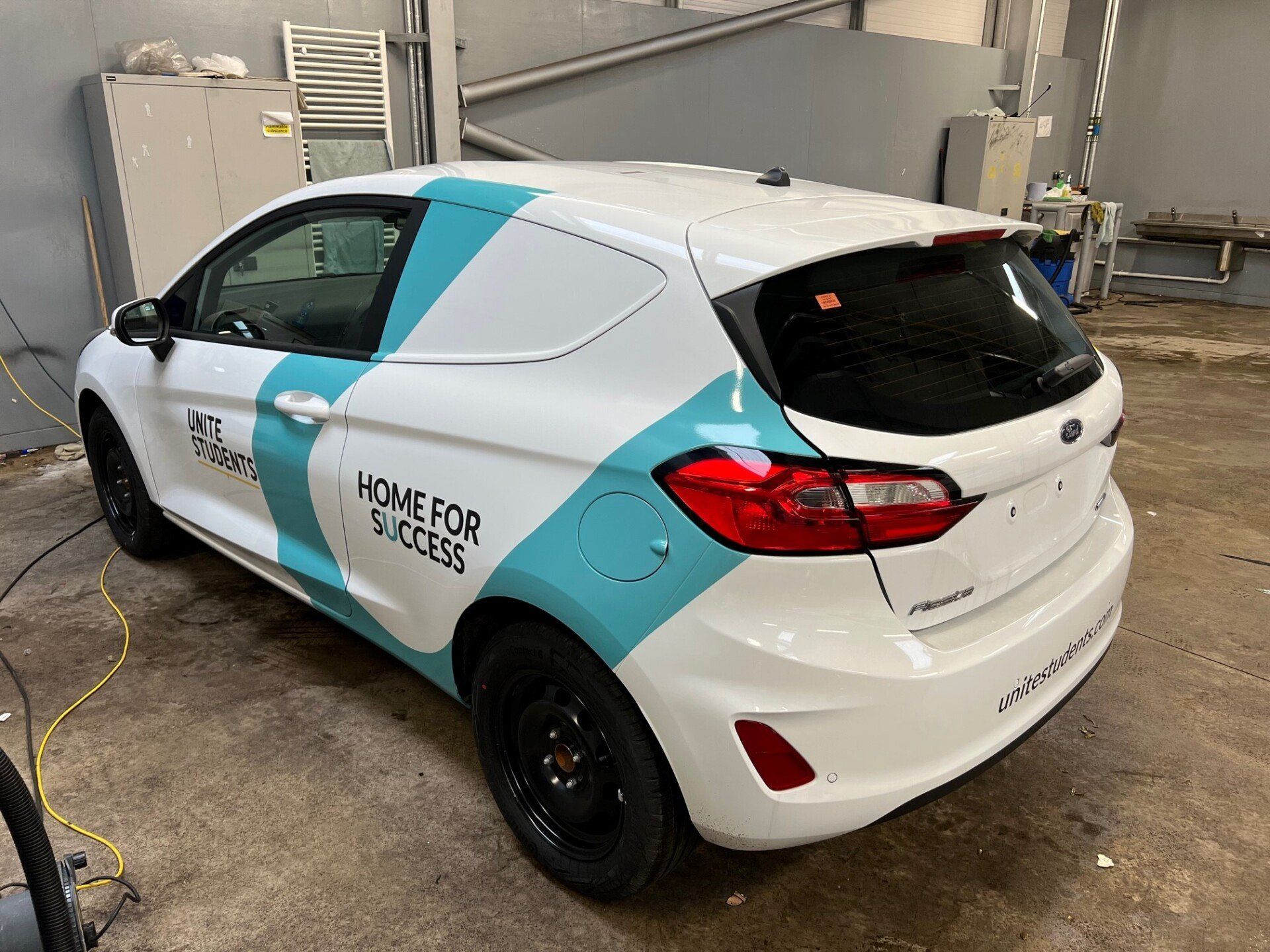 A white and blue car is parked in a garage.