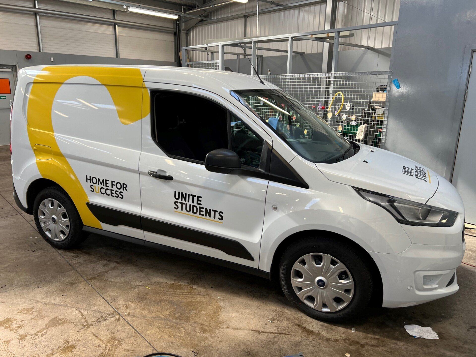 A white and yellow van is parked in a warehouse.