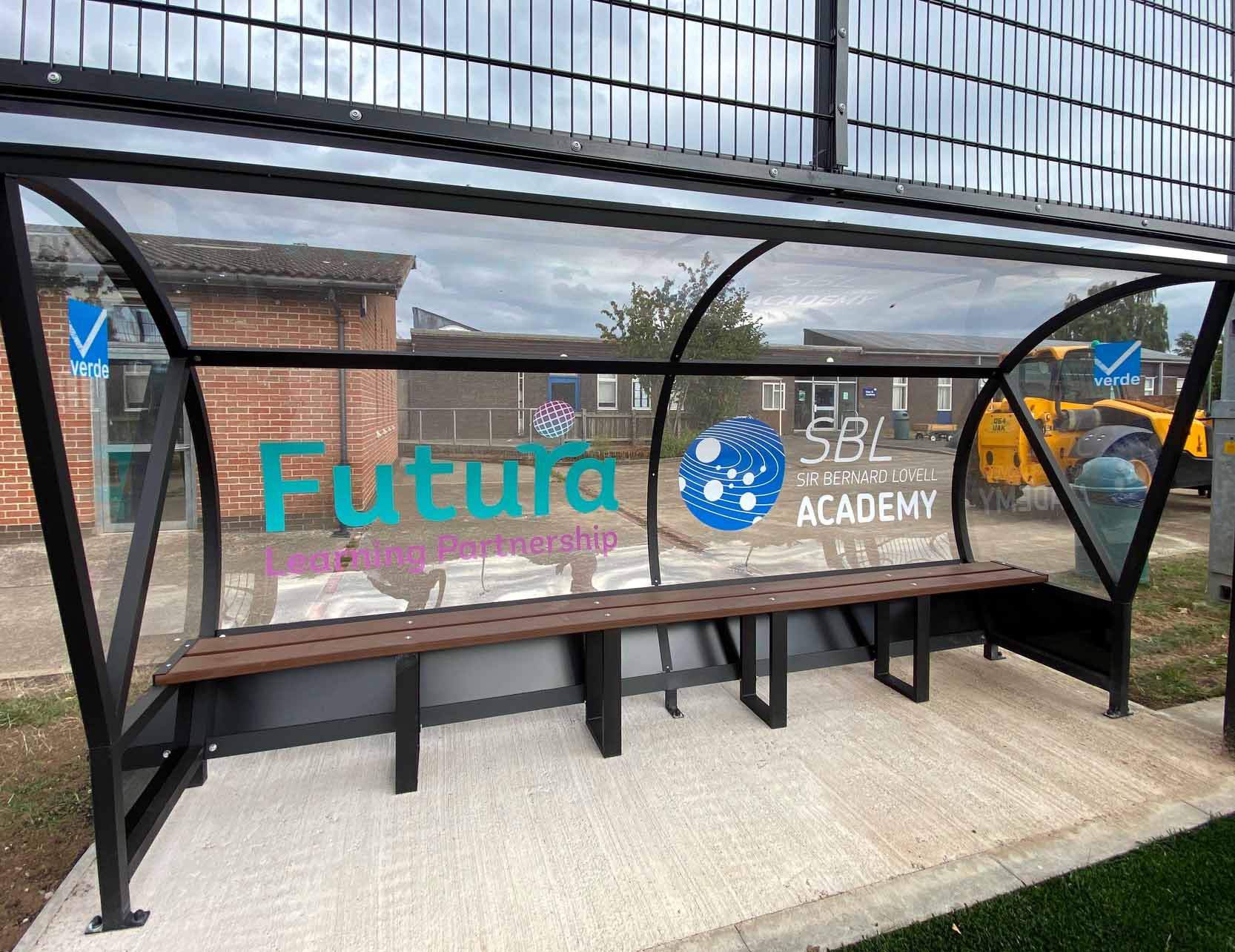 A shelter with a bench and a sign that says futura academy on it.
