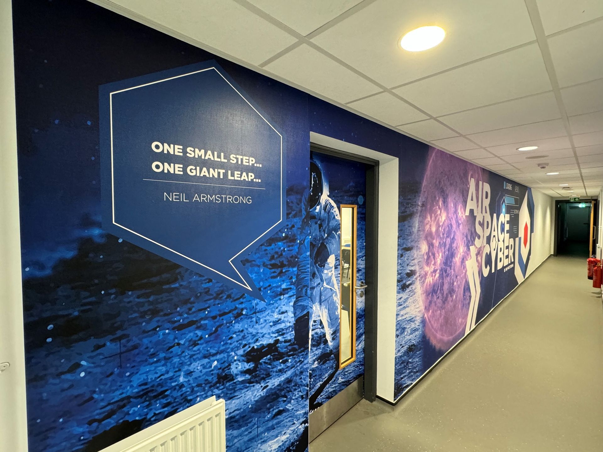 A hallway with a mural on the wall that says `` one small step one giant leap ''.