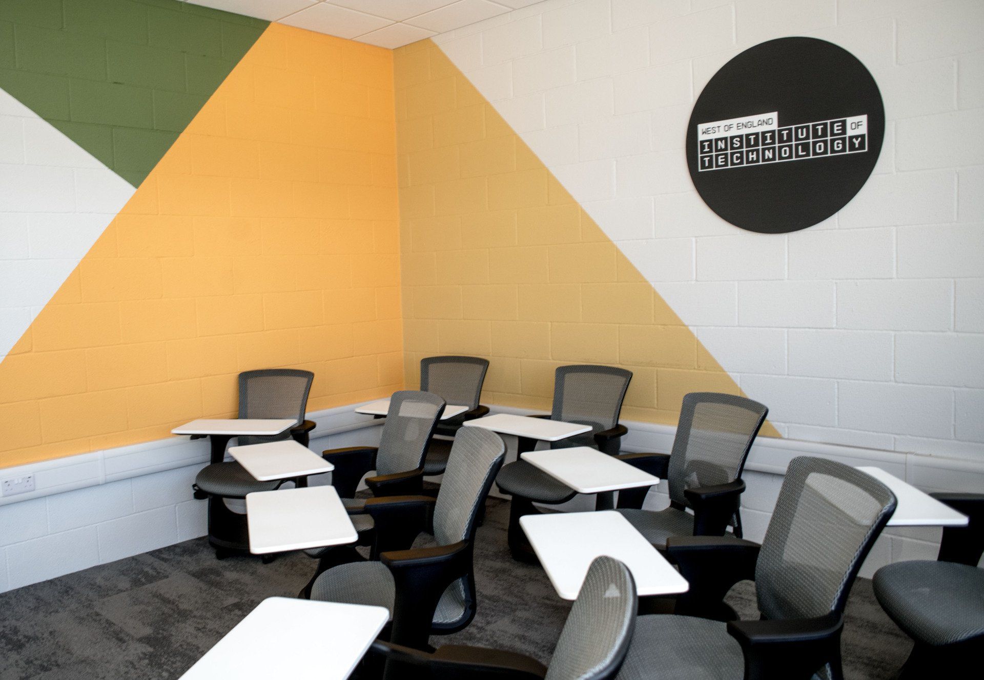 A classroom with tables and chairs and a sign on the wall
