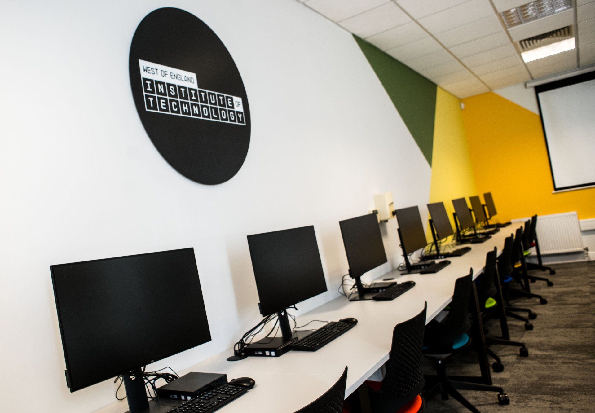 A row of computer monitors are lined up in a room.
