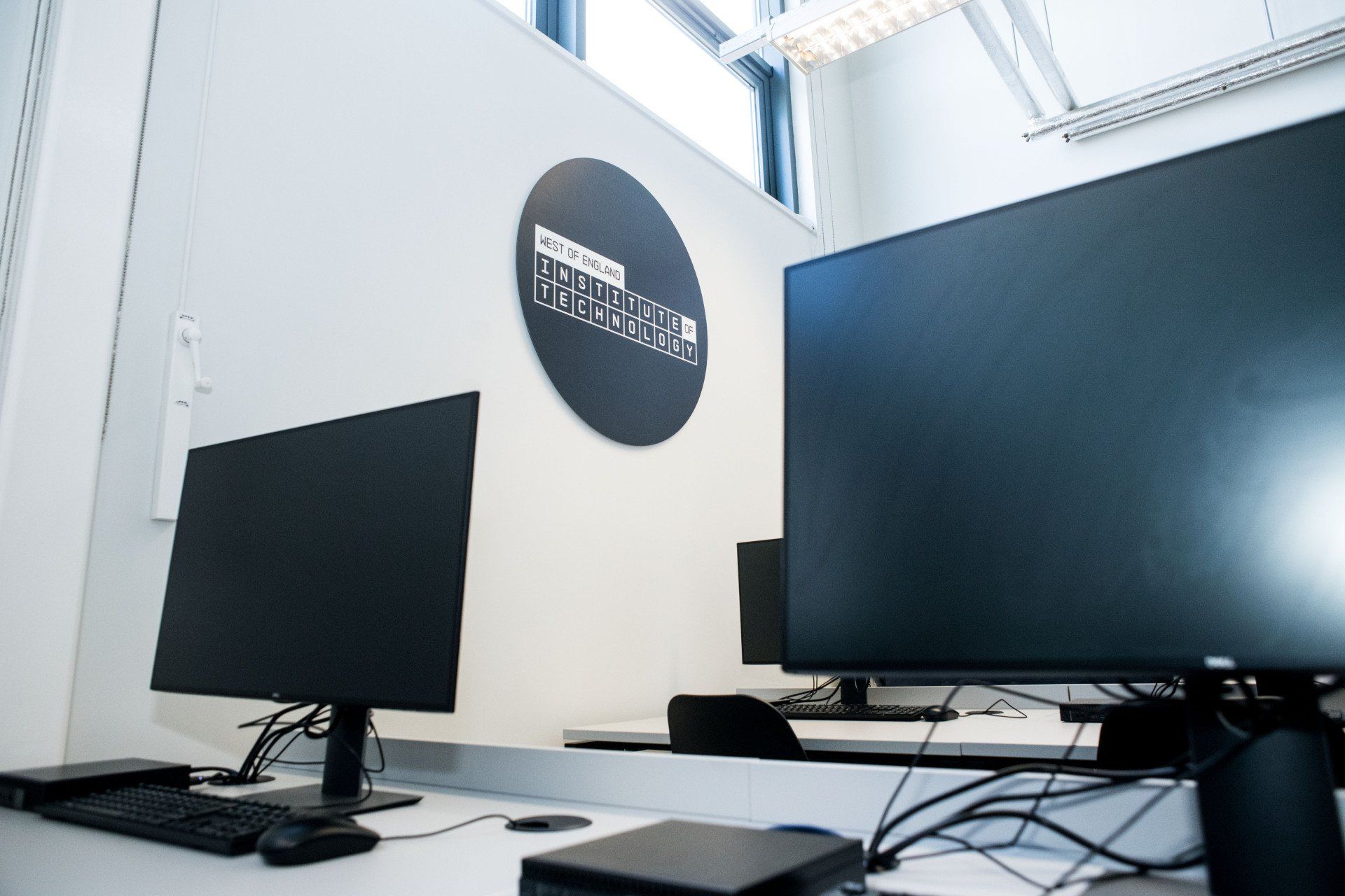 Two computer monitors are sitting on a desk in a room.