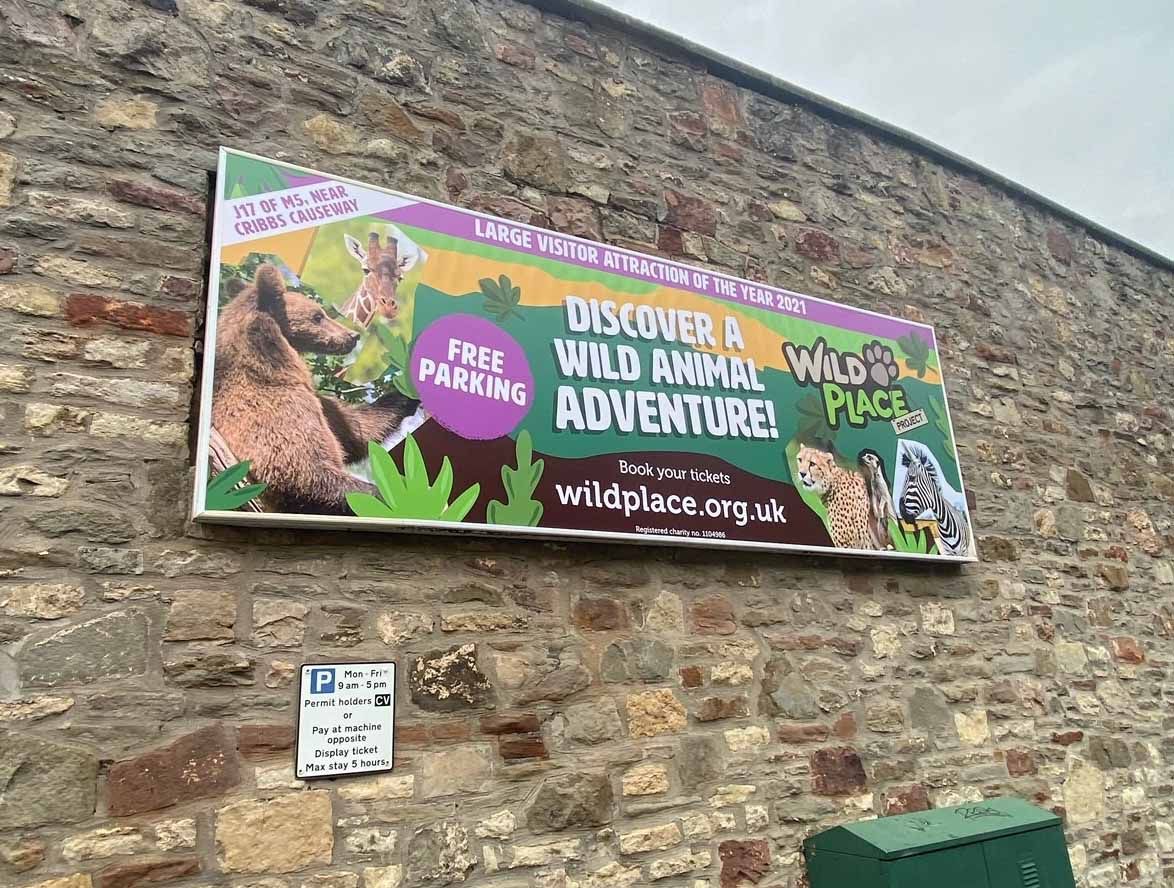 A large billboard on a brick wall advertising a wild animal adventure.