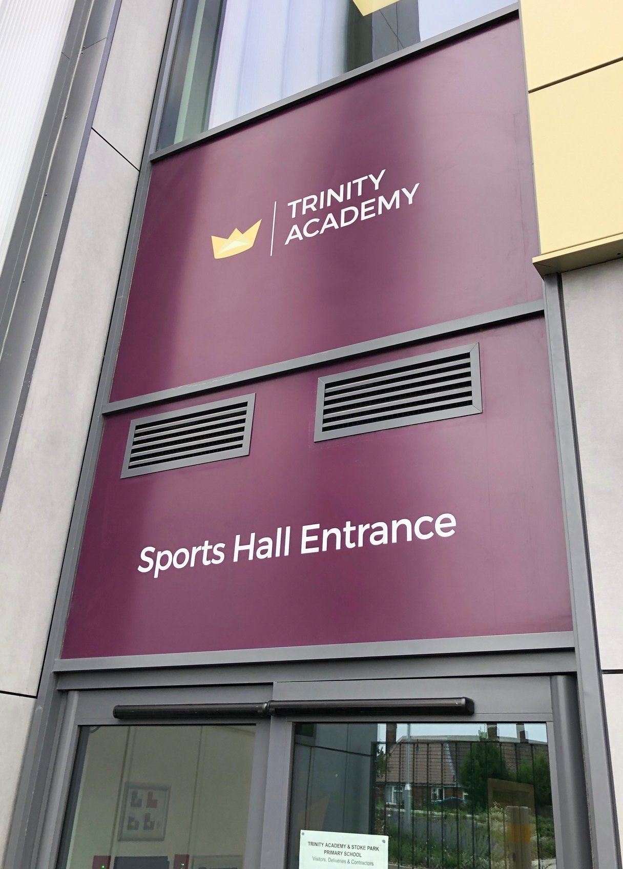 The trinity academy sports hall entrance is located on the side of a building.