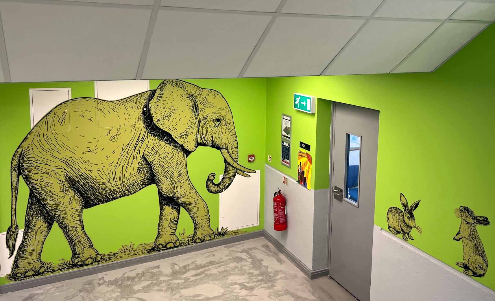 A painting of an elephant on a green wall