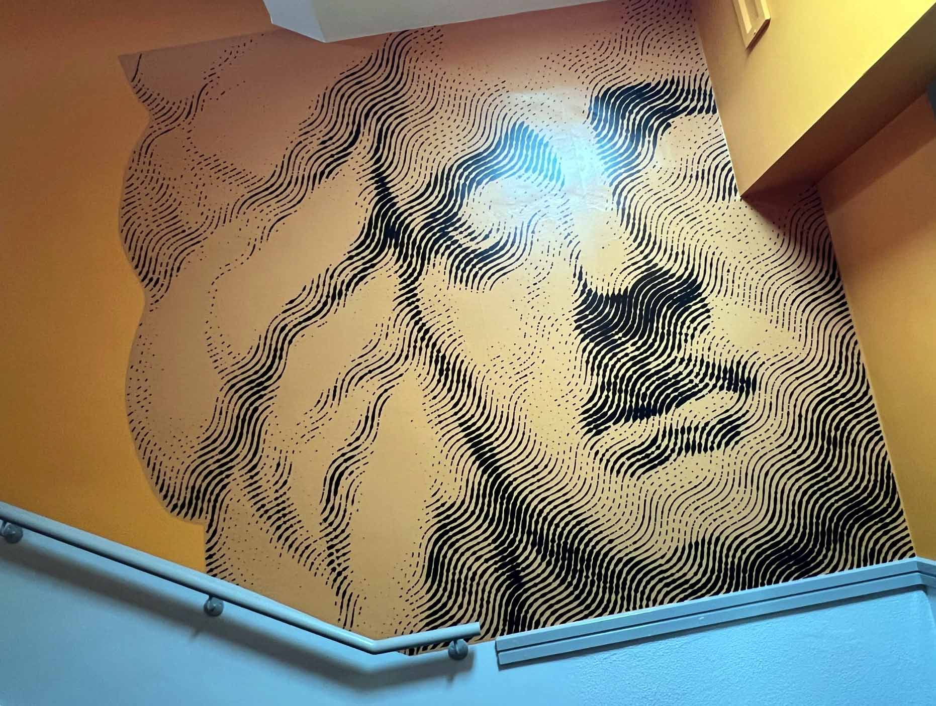 A staircase with a painting of a man 's face on the wall