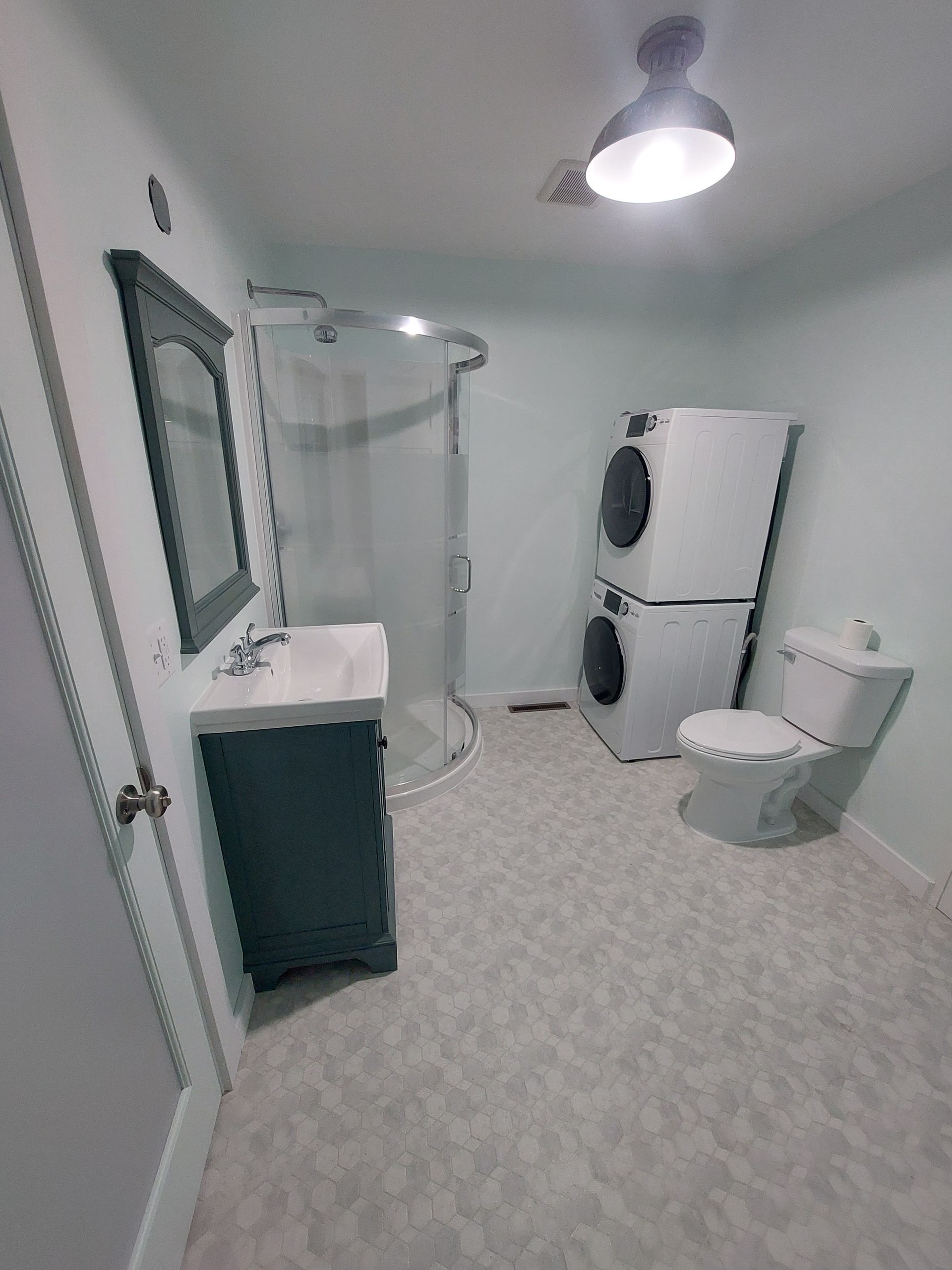 A bathroom with a sink , toilet , washer and dryer stacked on top of each other.