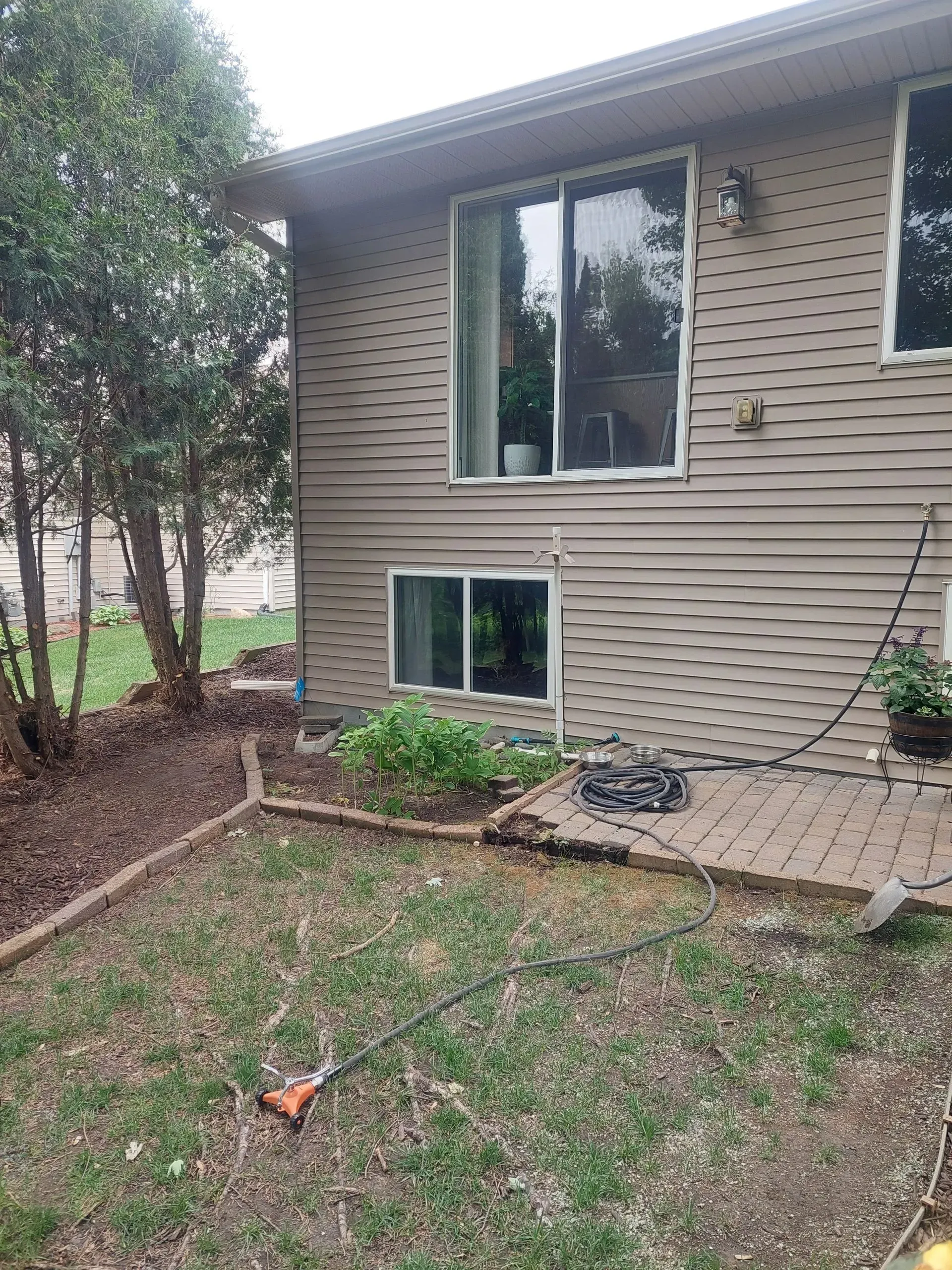 A house with a lot of windows and a patio in the backyard.