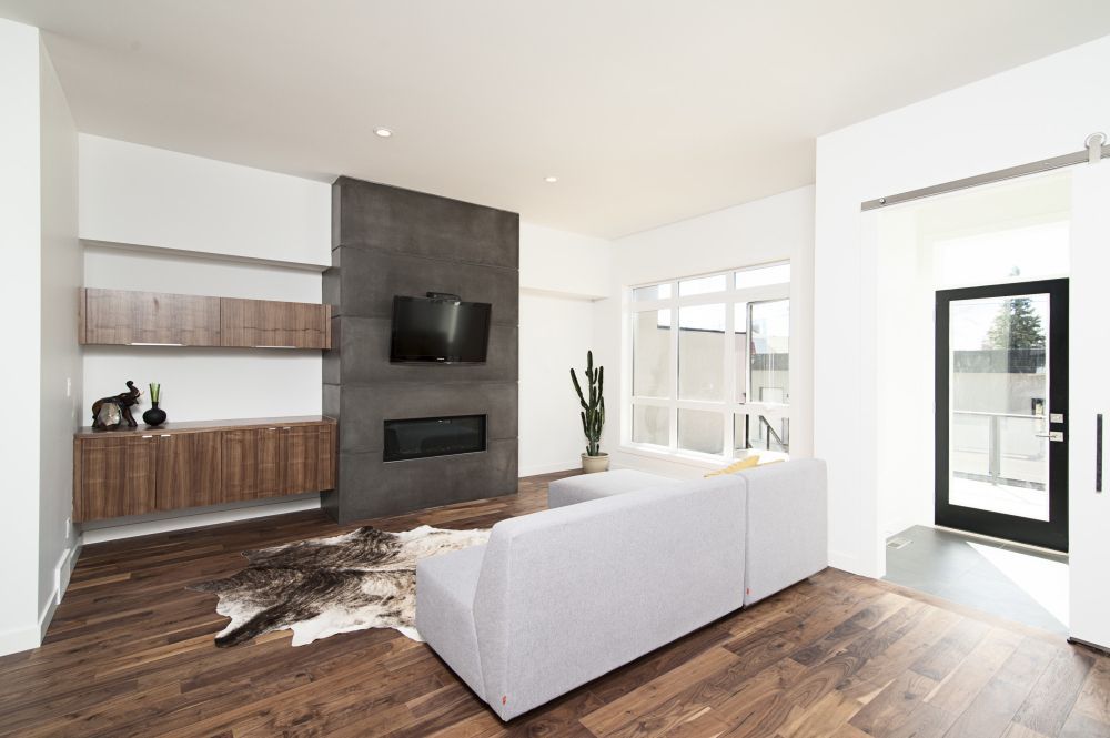 Modern living room with a fireplace, TV, white sofa, wooden floors, and a sliding door.