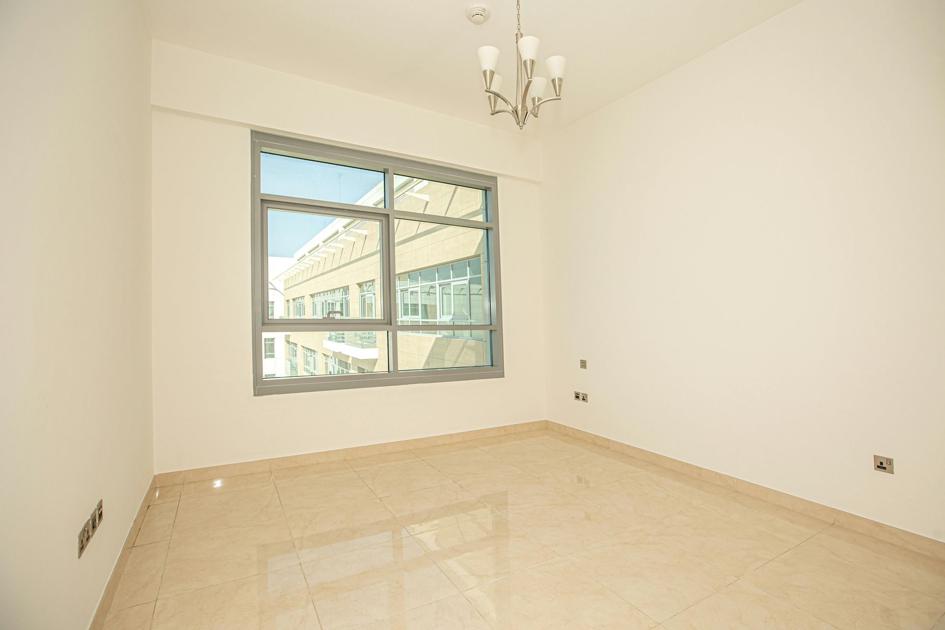 An empty room with a large window and a chandelier.
