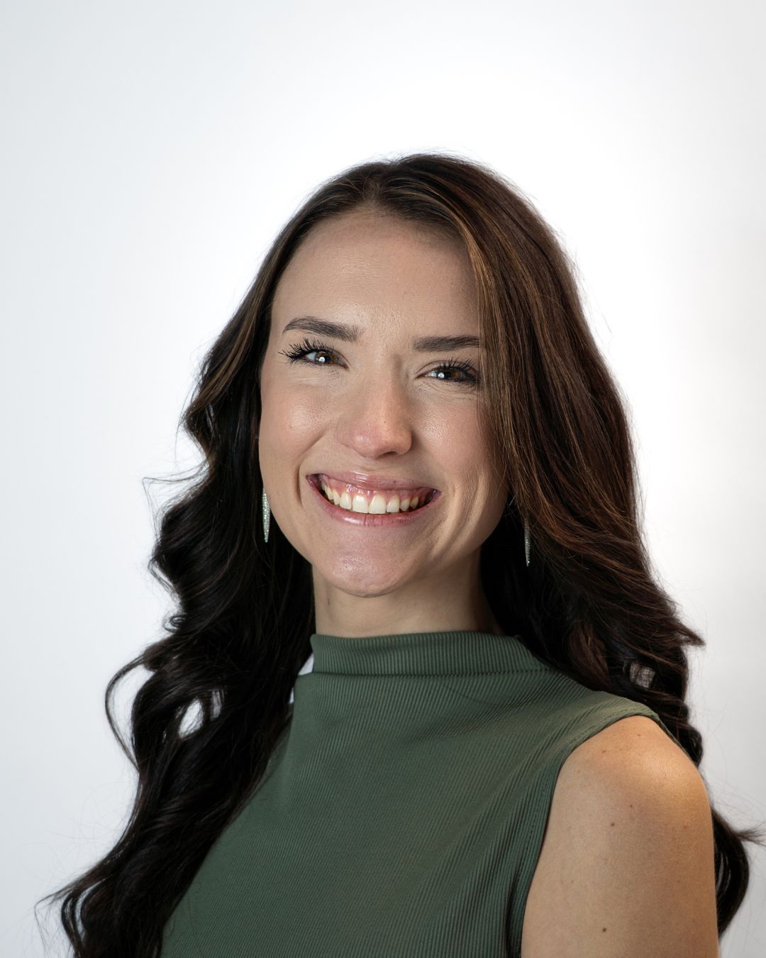 Smiling woman in a dark blazer against a gray studio backdrop