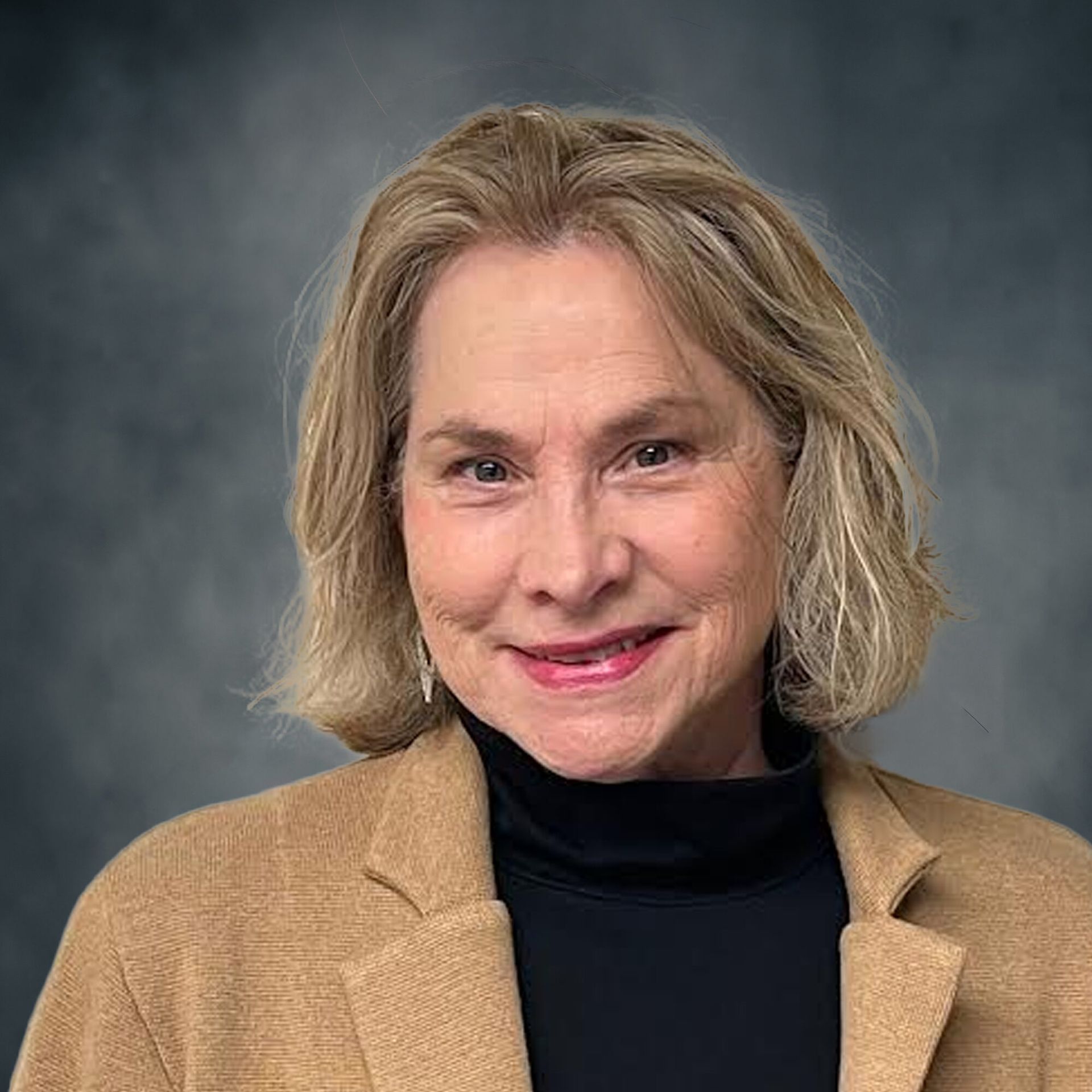 Portrait of a smiling woman in a tan blazer against a gray studio background