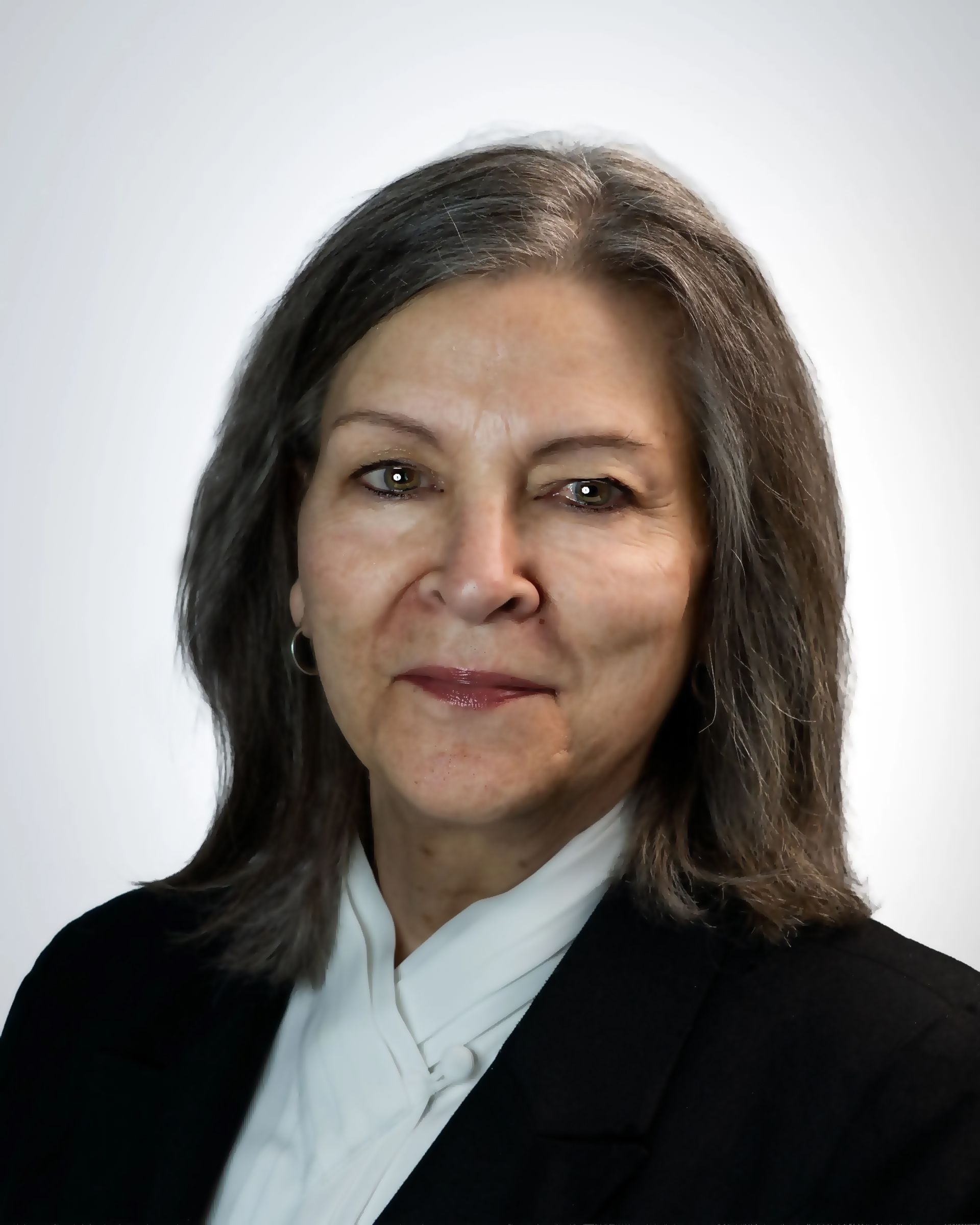 Portrait of a smiling person in a dark blazer and maroon shirt against a gray background
