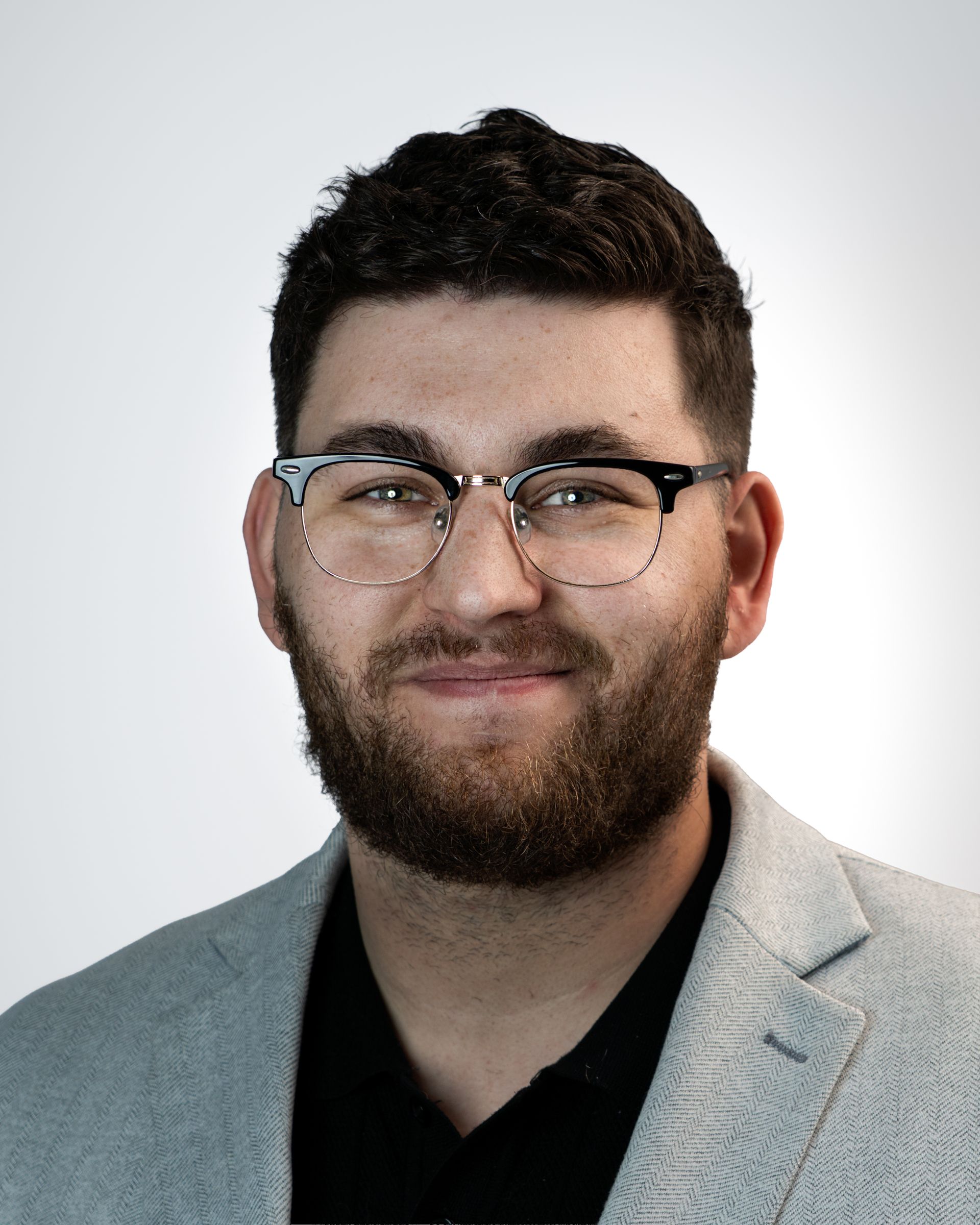 Studio portrait of a man in glasses and a blue blazer against a dark background