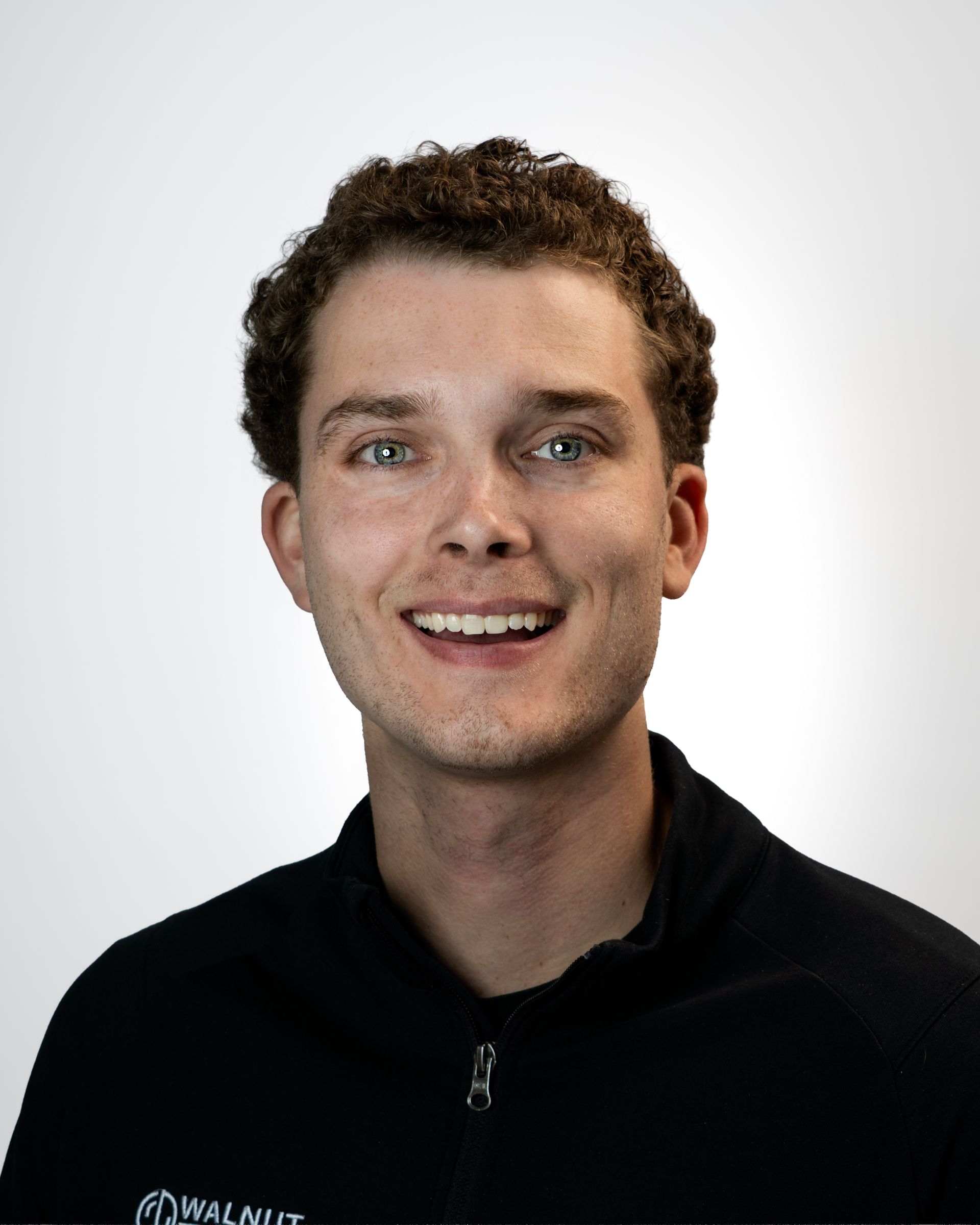 Portrait of a smiling person in a blue blazer and white shirt against a gray studio backdrop