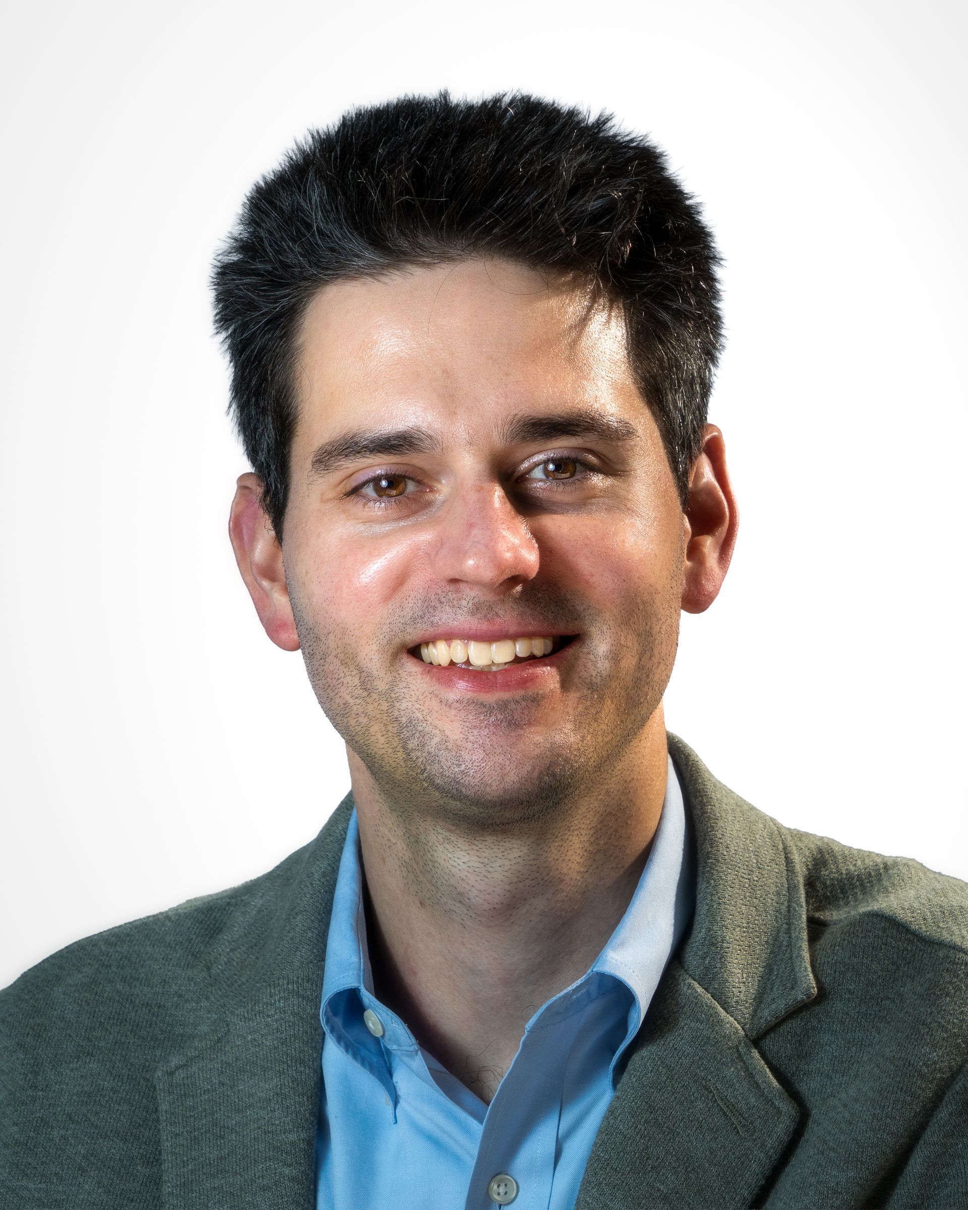 Studio portrait of a smiling man in a gray blazer and maroon shirt on a gray background