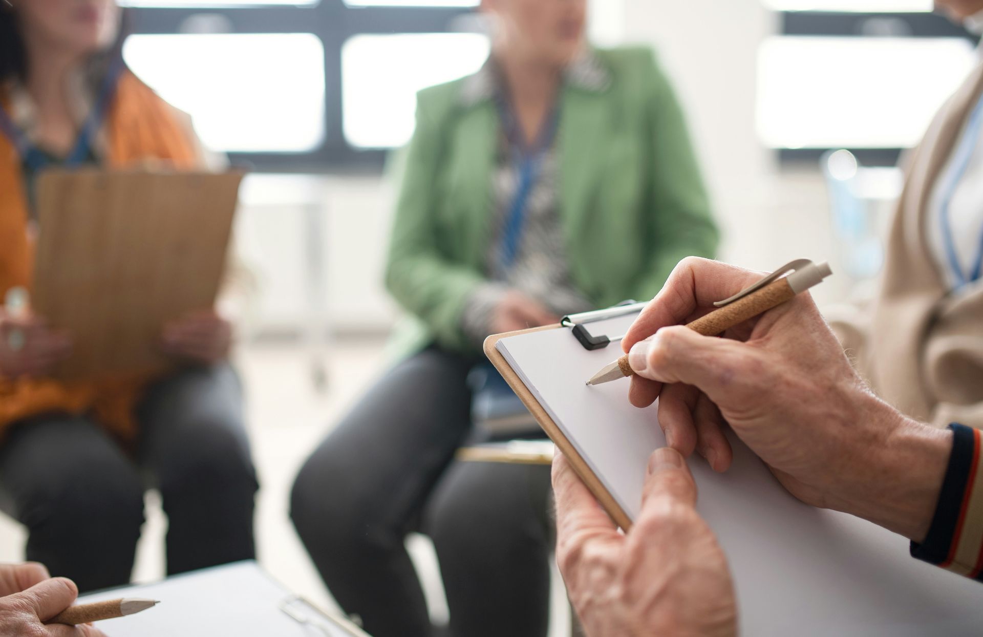 A person is writing on a clipboard in front of a group of people.