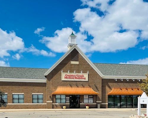 Stoneway Square storefront with stone facade, orange awnings, and a blue sky with clouds