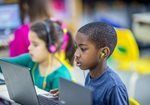 Children wearing headsets using laptops in a classroom