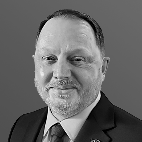 Man with a beard, wearing a suit and tie, smiling at the camera.