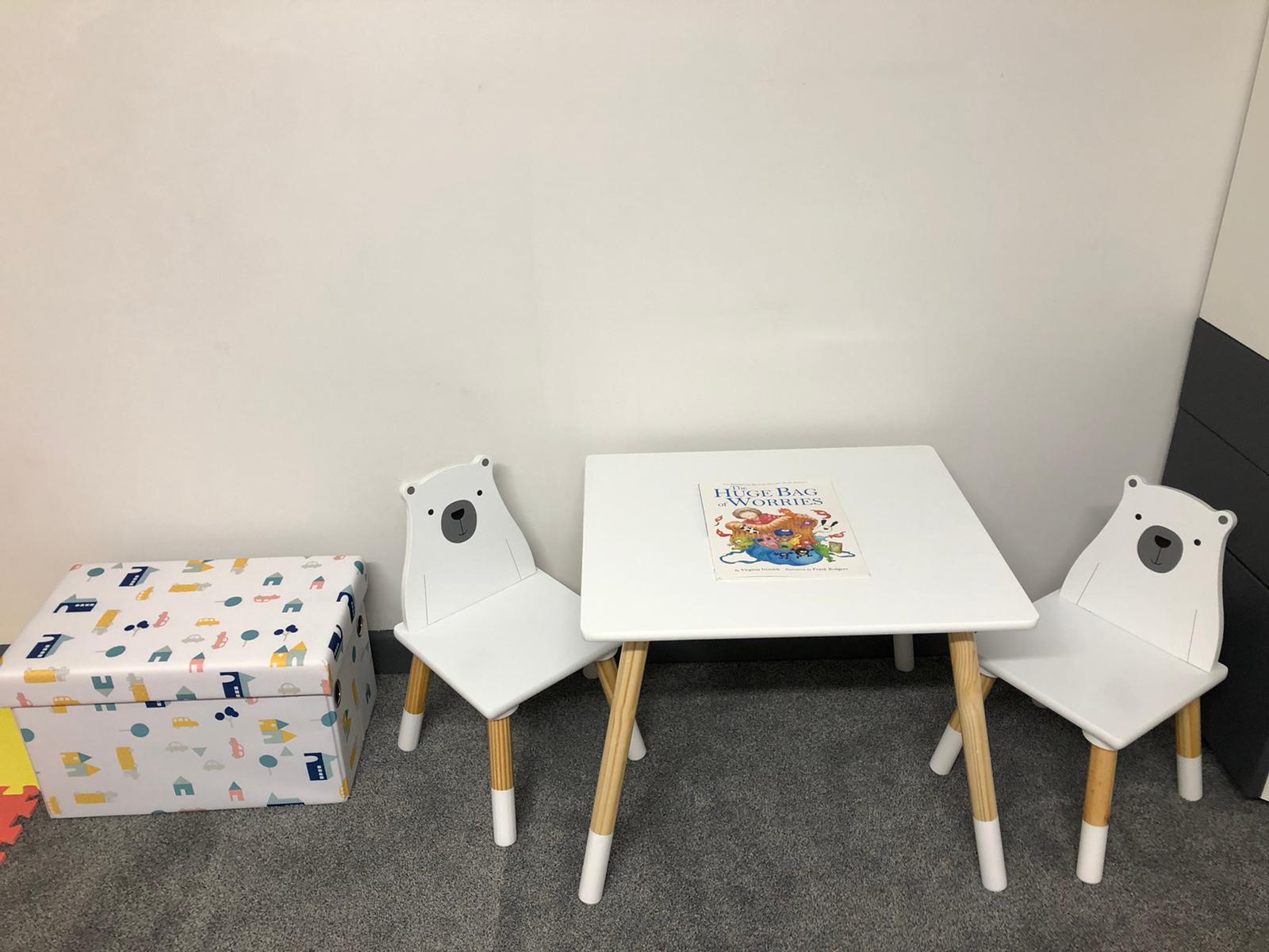 A white table with two chairs and a box on the floor. Dramatherapy Ireland