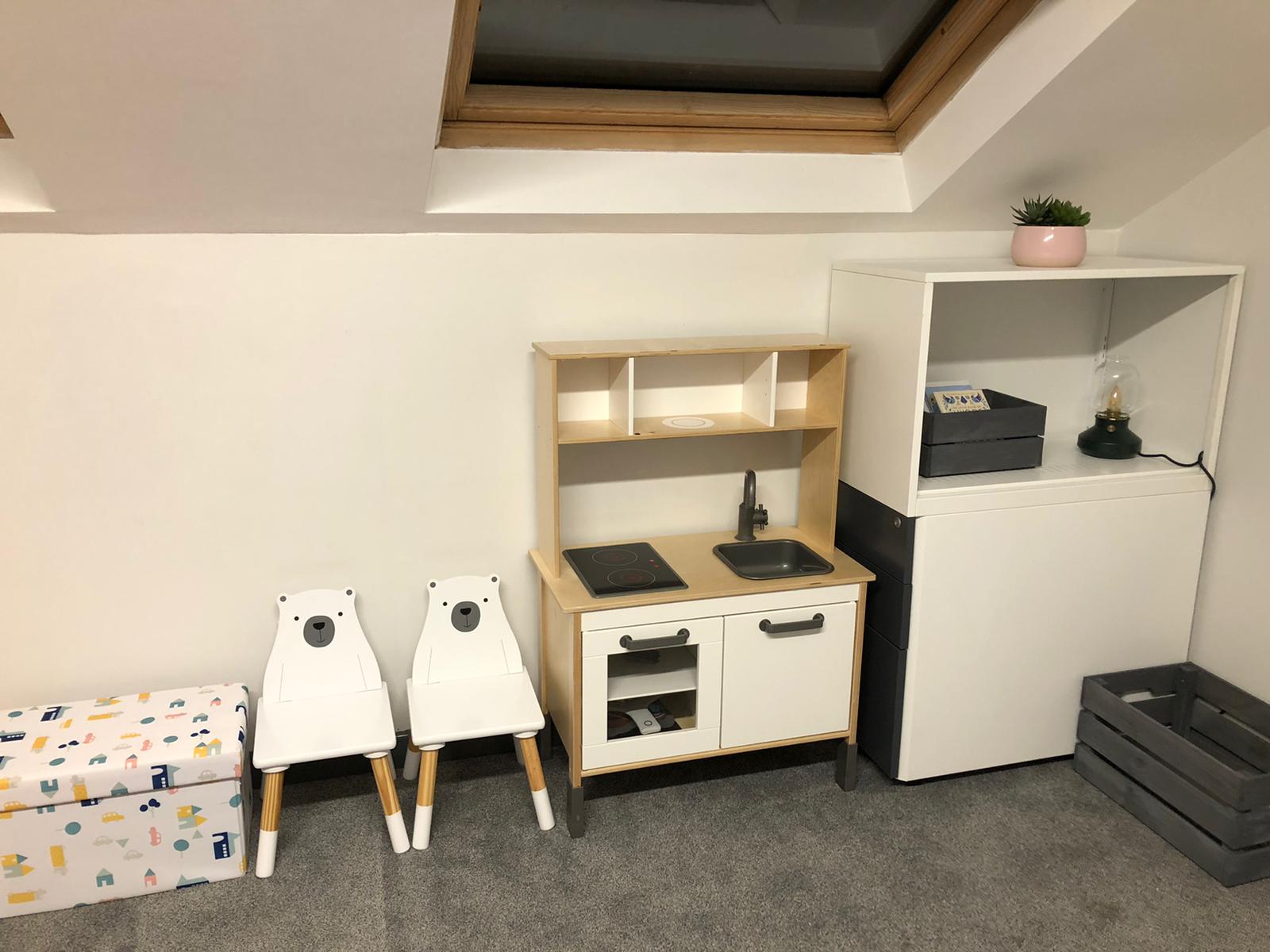 A room with a play kitchen , chairs , boxes and a window. Dramatherapy Ireland